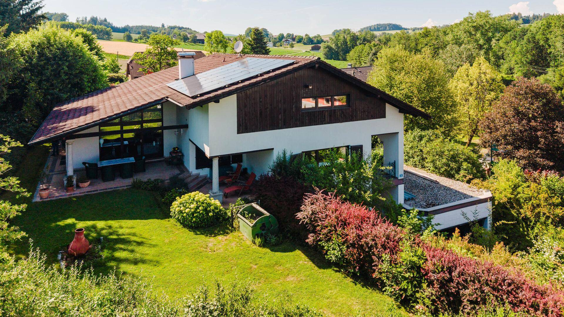 Rückansicht des Hauses mit Garten, Terrasse und Photovoltaikanlage auf dem Dach.