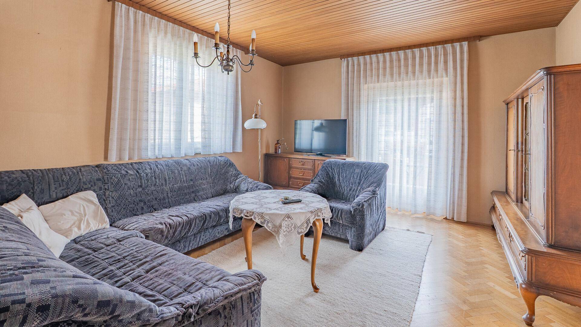 Wohnzimmer mit großem Sofa, Fernseher und Holzboden, hell und einladend.