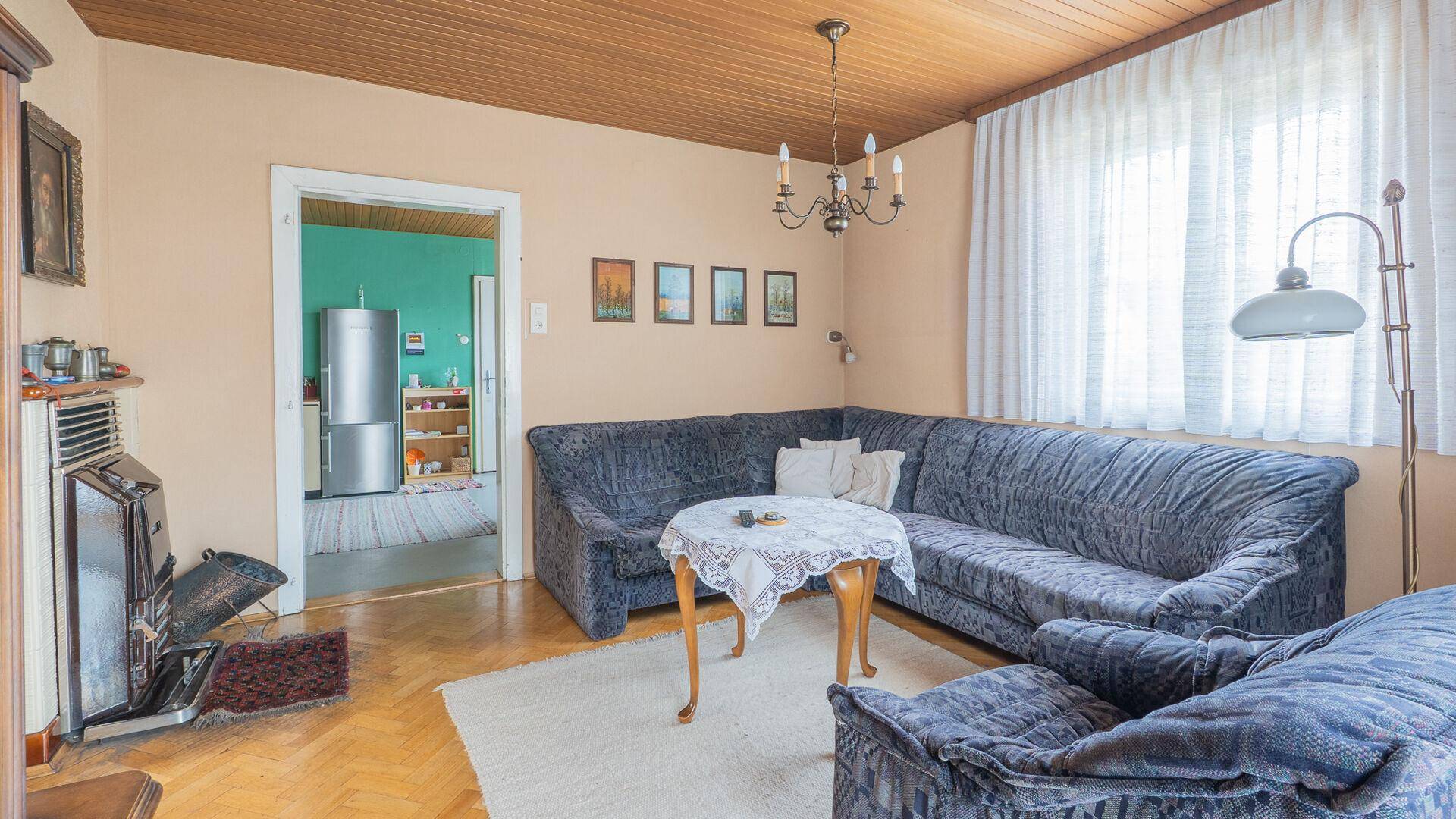 Gemütliches Wohnzimmer mit Holzboden, Kaminofen und Zugang zur Küche.