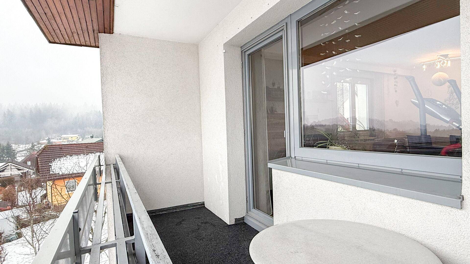 Kleiner Balkon mit Tisch und Blick auf die verschneite Umgebung.