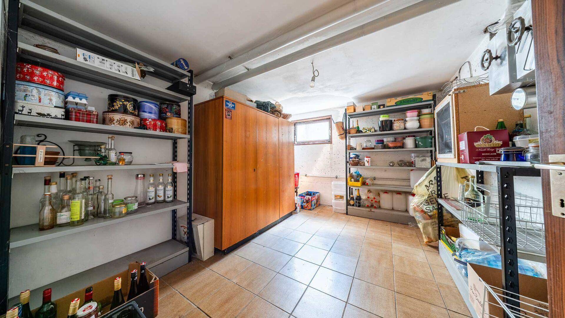 Geräumiger Vorratsraum mit zahlreichen Regalen und einem großen Holzschrank, ideal für Lagerung.