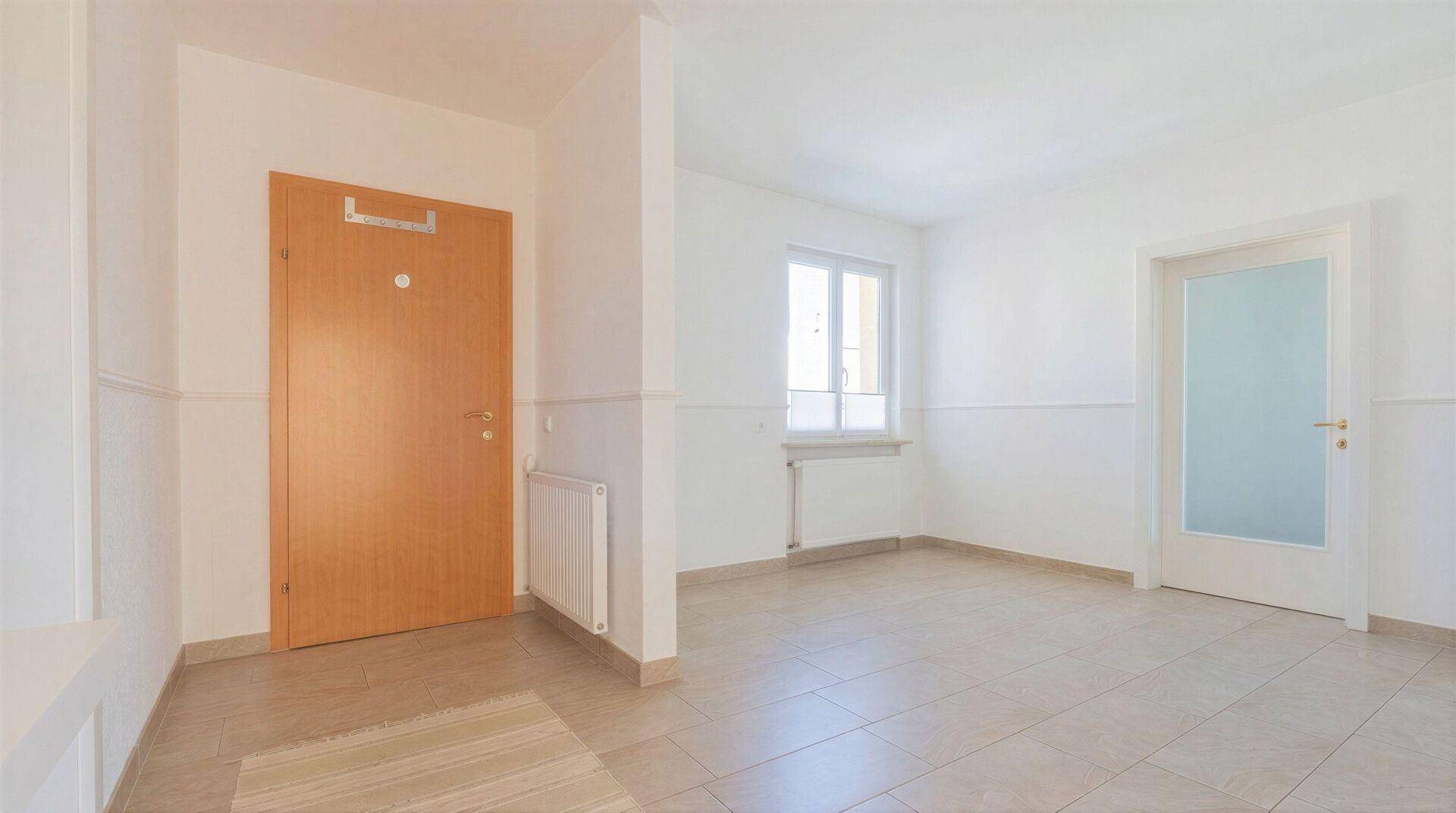 Eingangsbereich mit Fliesenboden und einer Holztür, die zu den Wohnräumen führt.