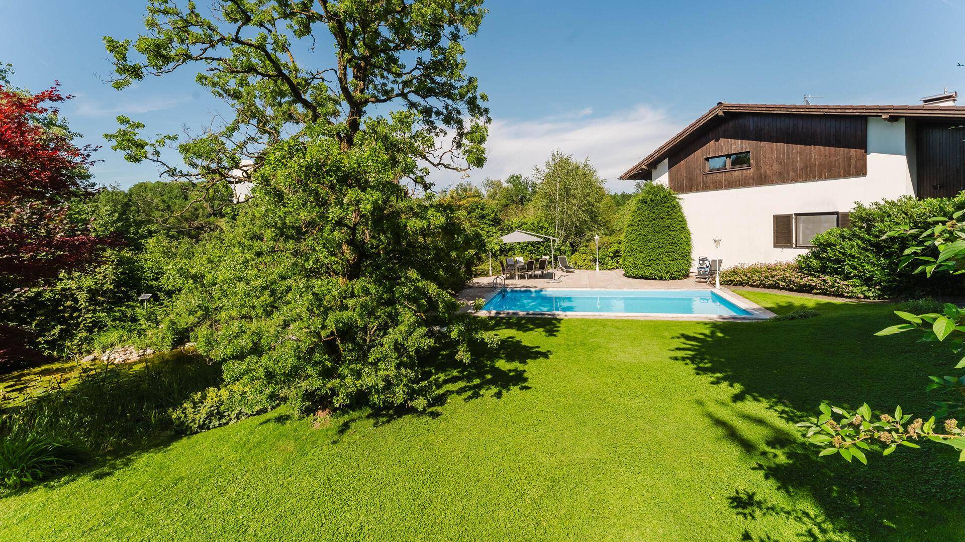 Großer, gepflegter Garten mit Rasenfläche, Pool und altem Baumbestand.