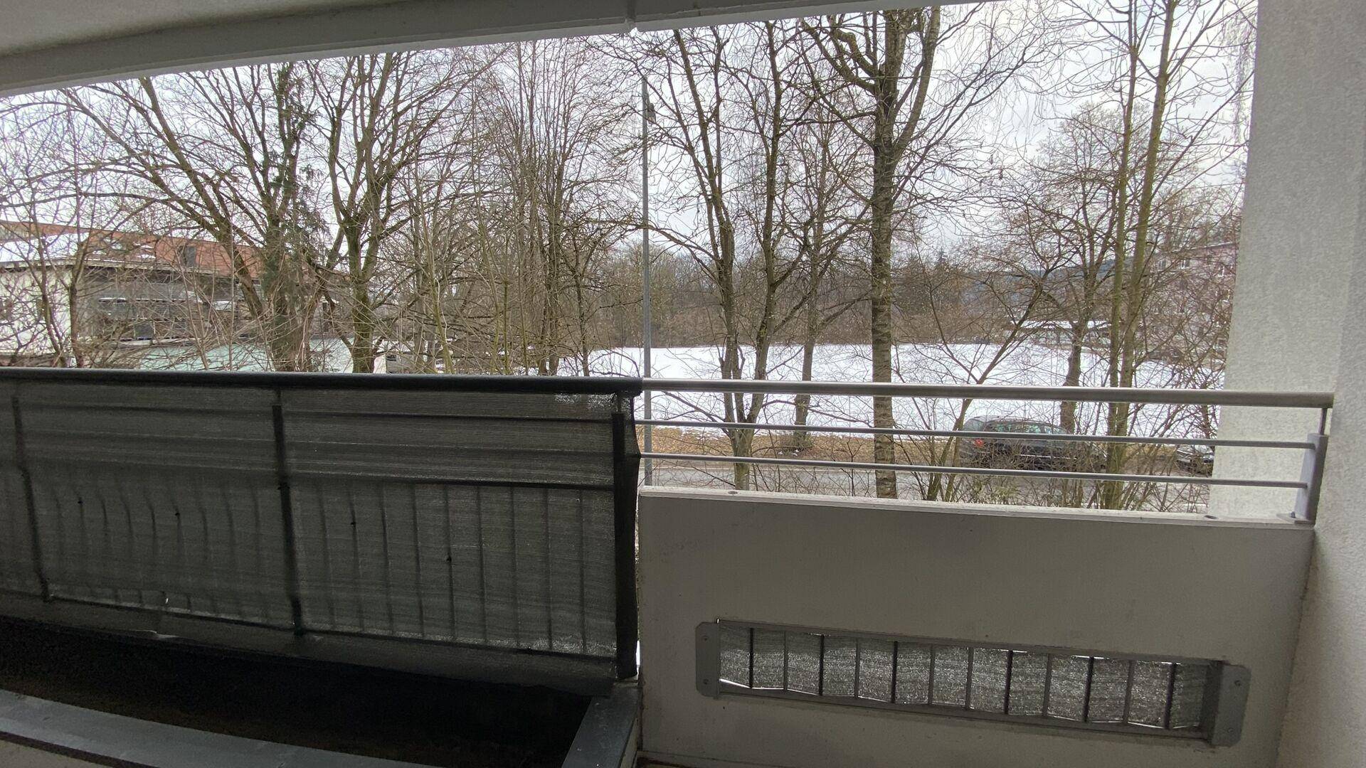 Balkon mit Blick auf verschneite Bäume und eine offene Landschaft im Winter.
