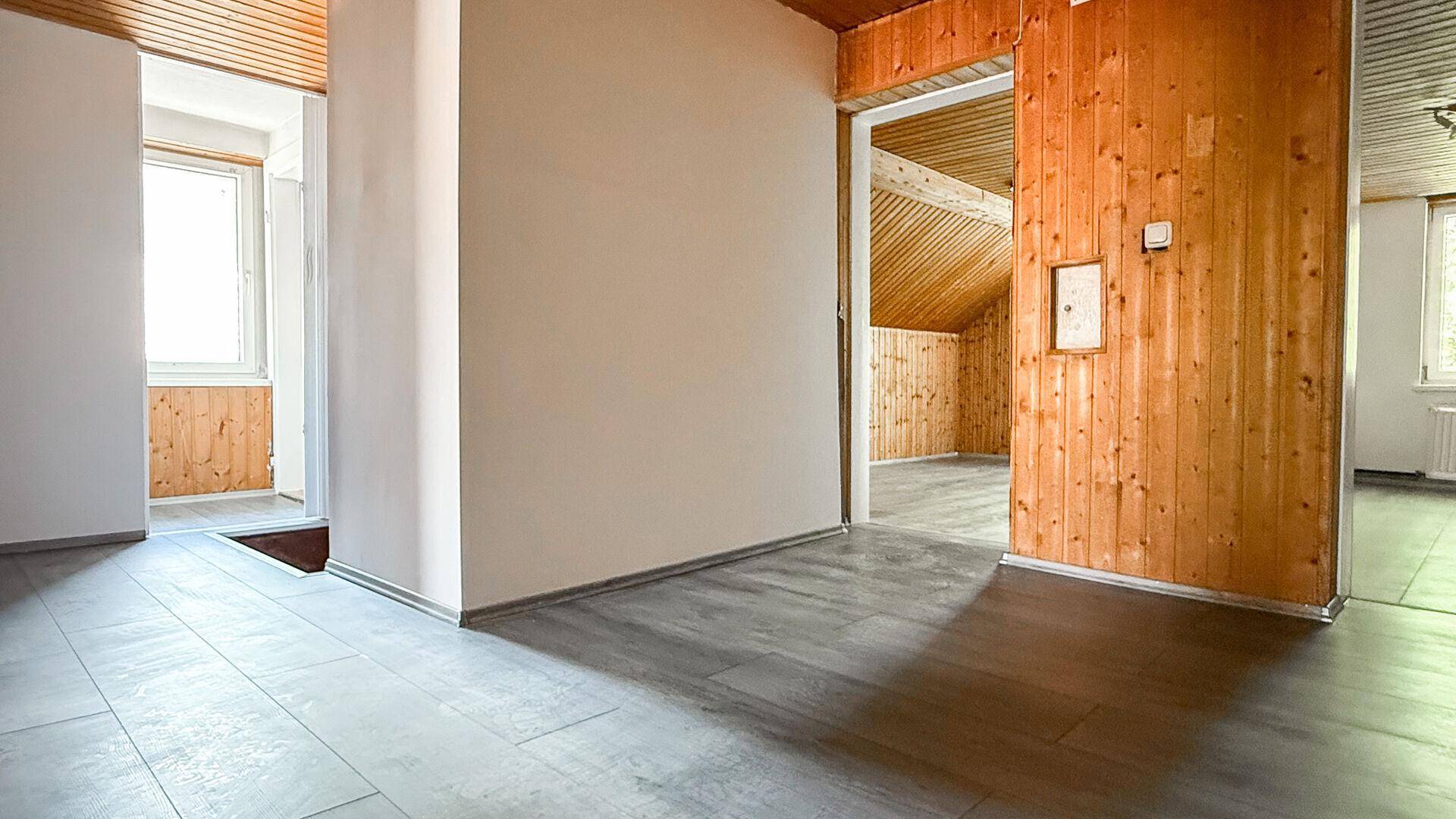 Flur mit hellem Laminatboden und Übergängen zu holzvertäfelten Räumen im Dachgeschoss.