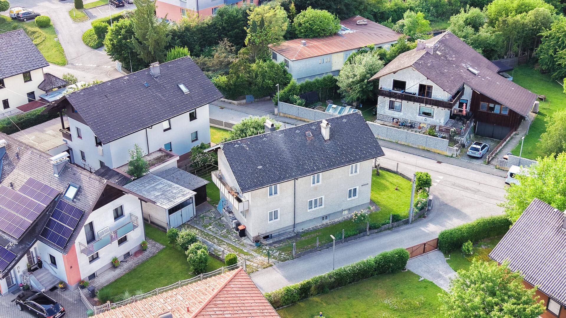 Luftaufnahme des Hauses und der umliegenden Wohngegend mit viel Grün und Dächern.