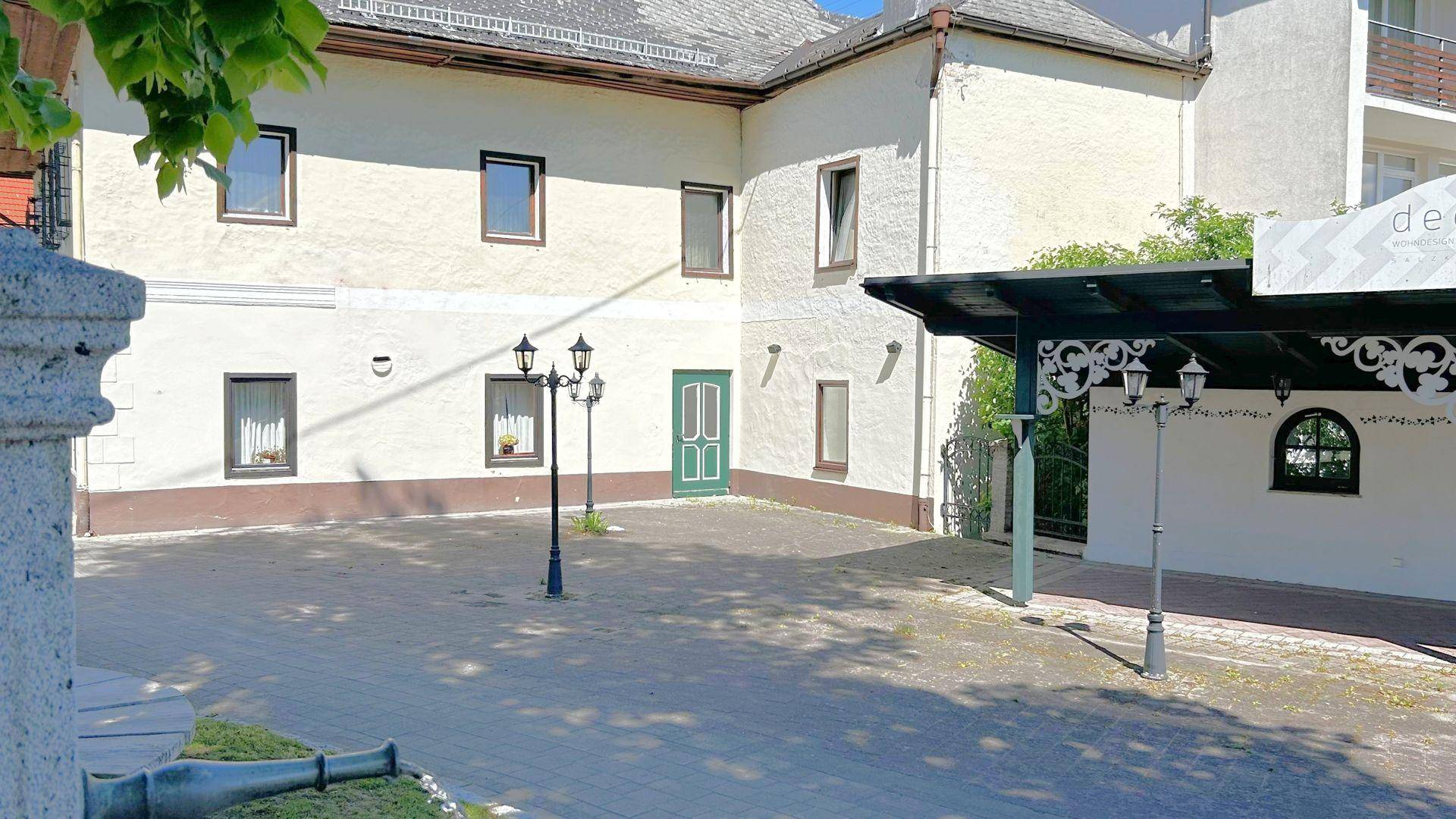 Gepflasterter Innenhof mit Laternen, einem Brunnen und dem Gebäude im Hintergrund.