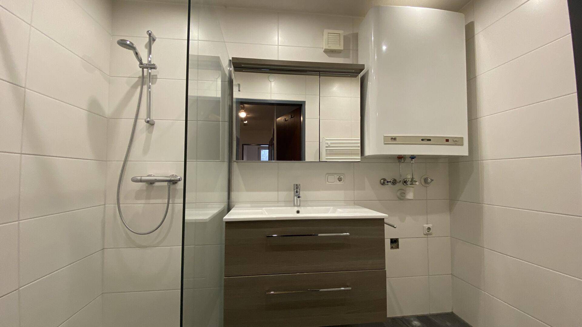 Modernes Badezimmer mit Duschkabine, Waschbecken und weiß gefliesten Wänden.