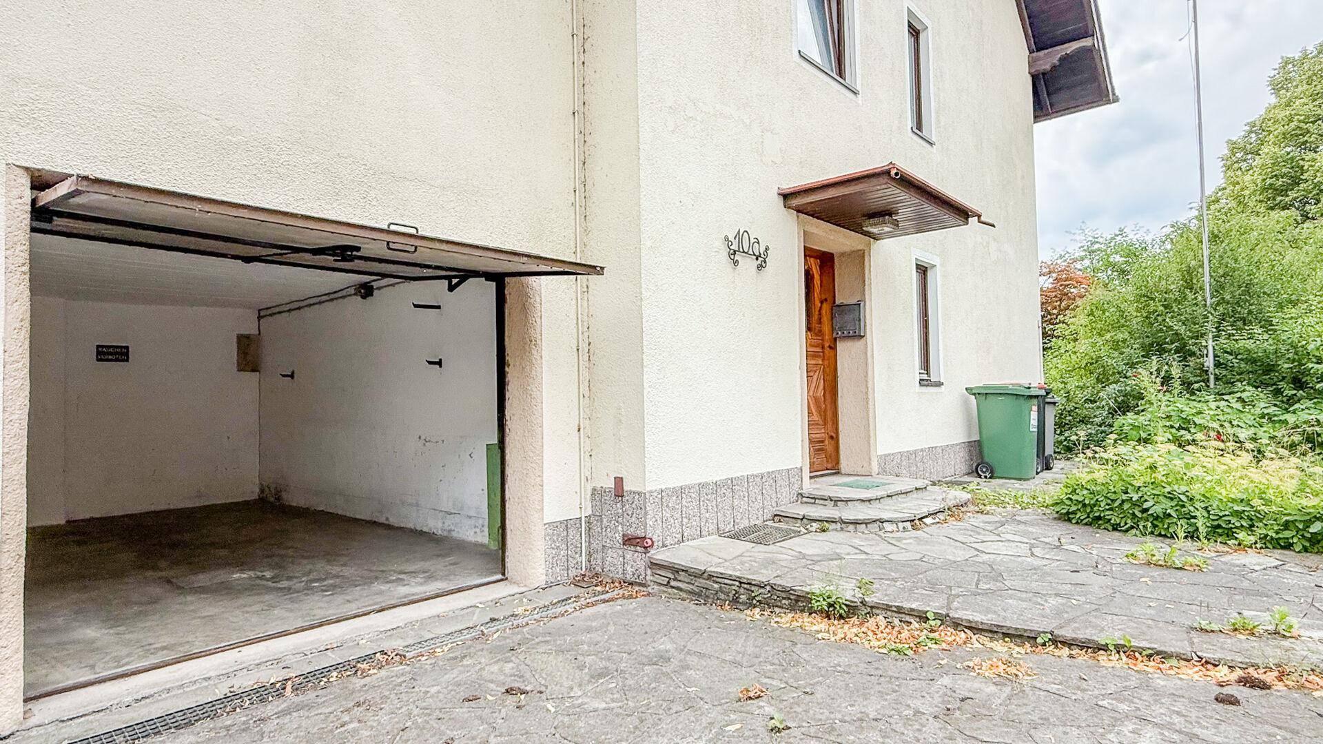 Offene Garage mit leerem Innenraum neben dem Haupteingang des Hauses.
