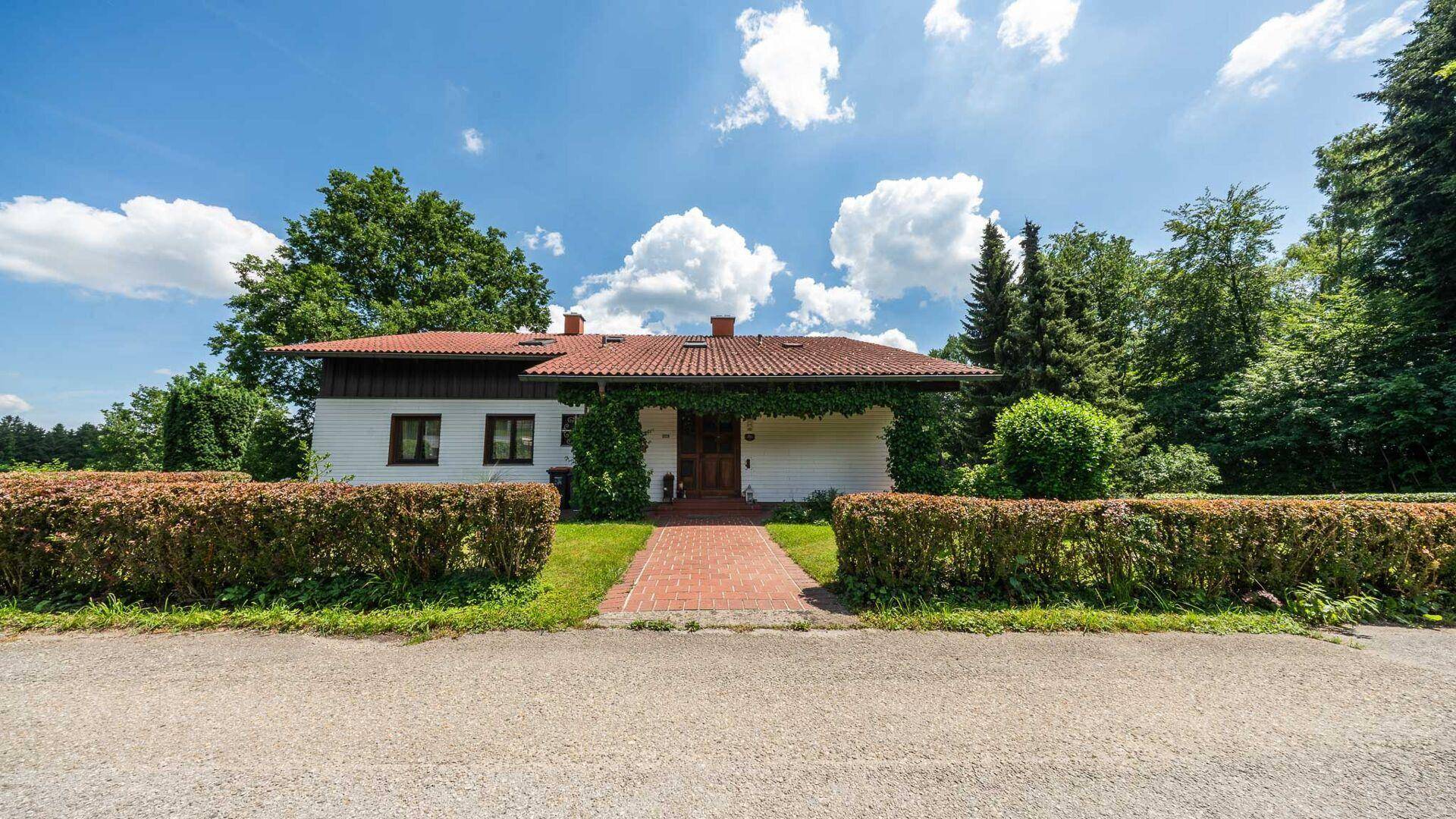 Vorderansicht des Hauses von der Straße aus, mit gepflegtem Vorgarten und Hecke.