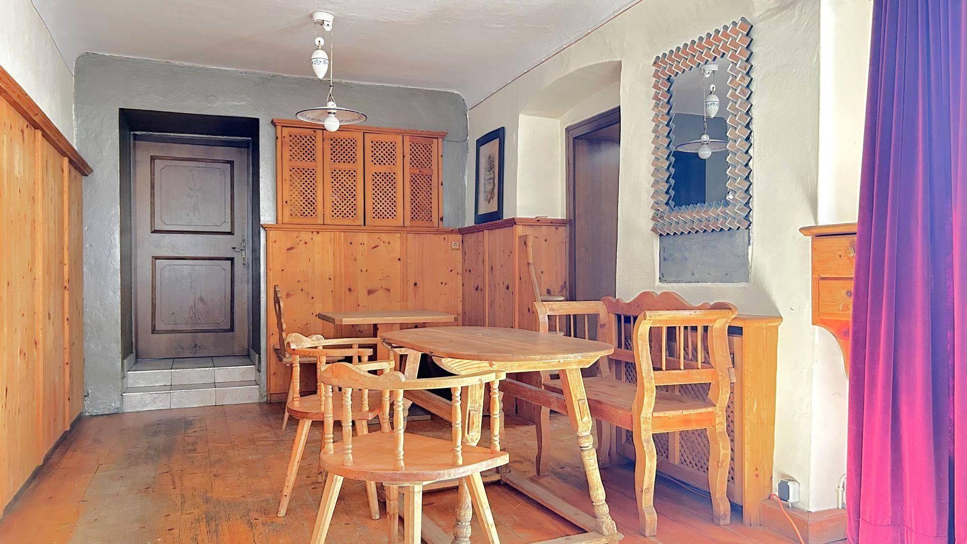 Essbereich mit Holztischen und Stühlen, Holzvertäfelung und einem großen Spiegel.