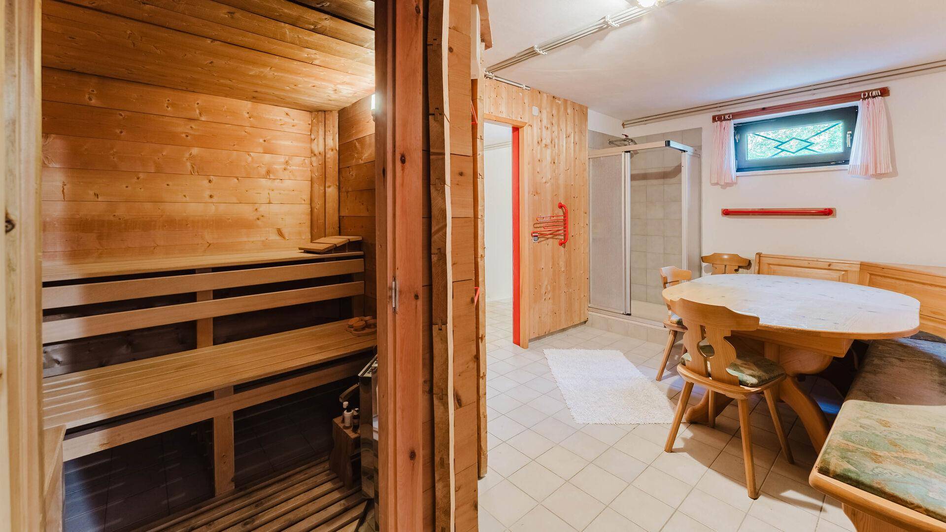 Wellnessbereich mit Sauna, Duschkabine und Sitzgelegenheiten.