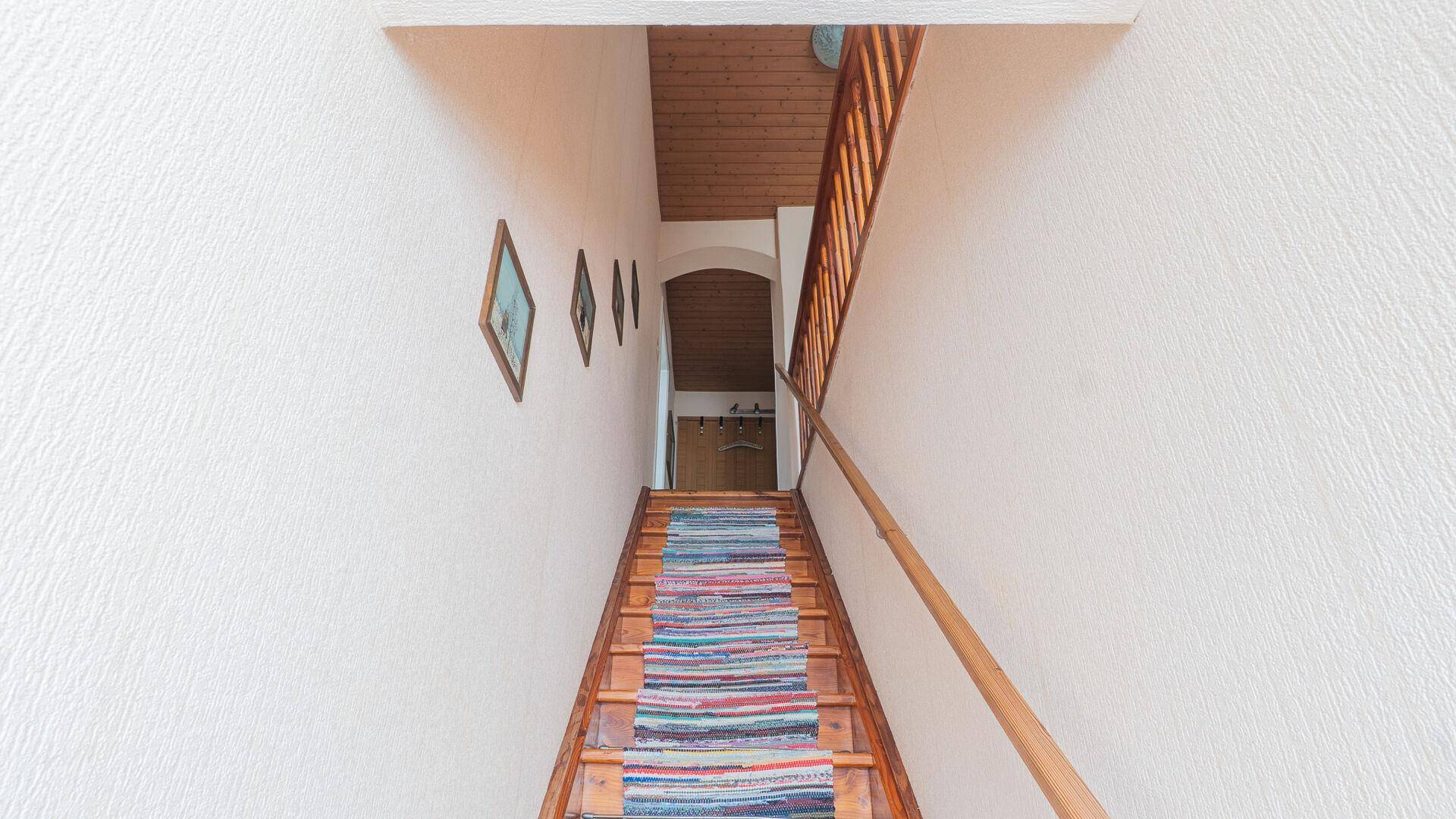 Holztreppe mit Teppichläufer führt in den oberen Bereich des Hauses.