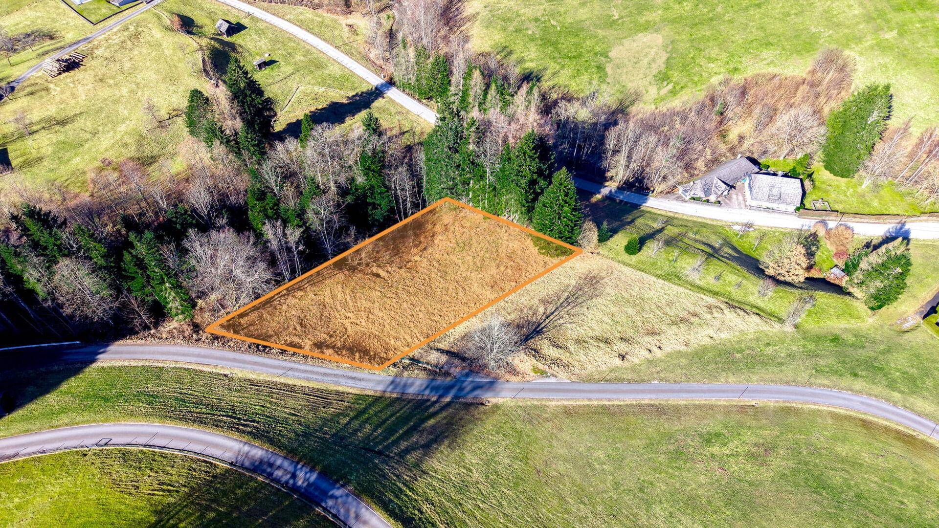 Luftaufnahme eines ländlichen Grundstücks, umrandet in Orange, umgeben von Feldern und Wald.