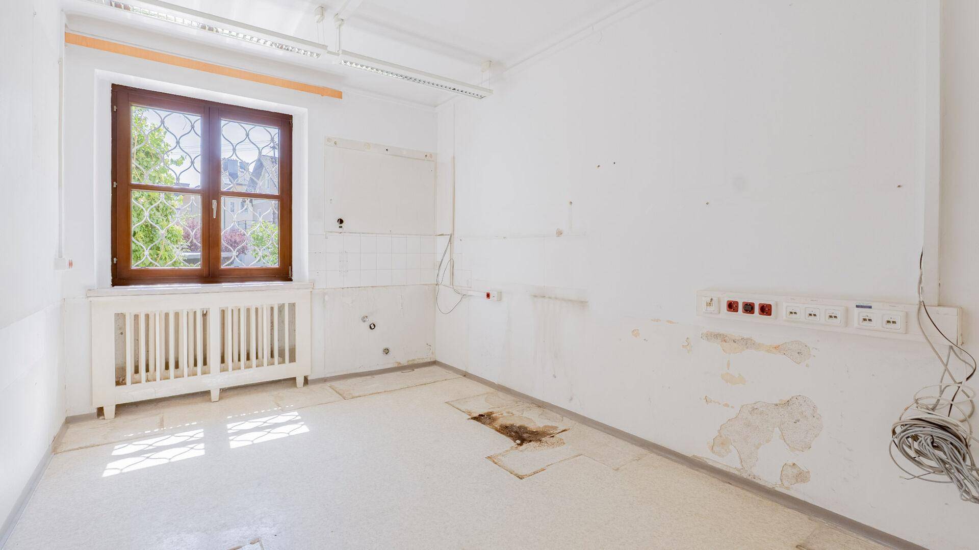 Unfertiger Raum mit Fenster und Heizkörper, bereit für den Ausbau oder die Renovierung.