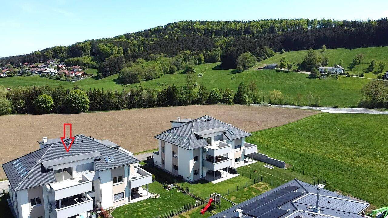 Luftaufnahme von zwei modernen Gebäuden in ländlicher Umgebung mit Spielplatz und Feldern.