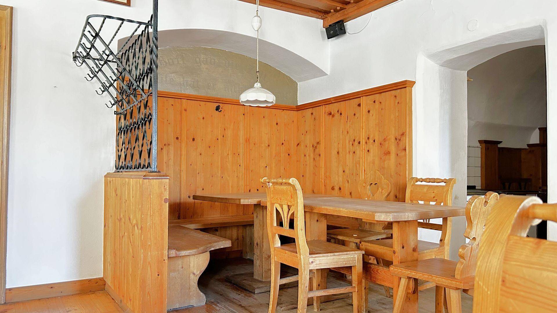 Traditioneller Essbereich mit Holztischen, Bänken und Stühlen, sowie einer Garderobe.