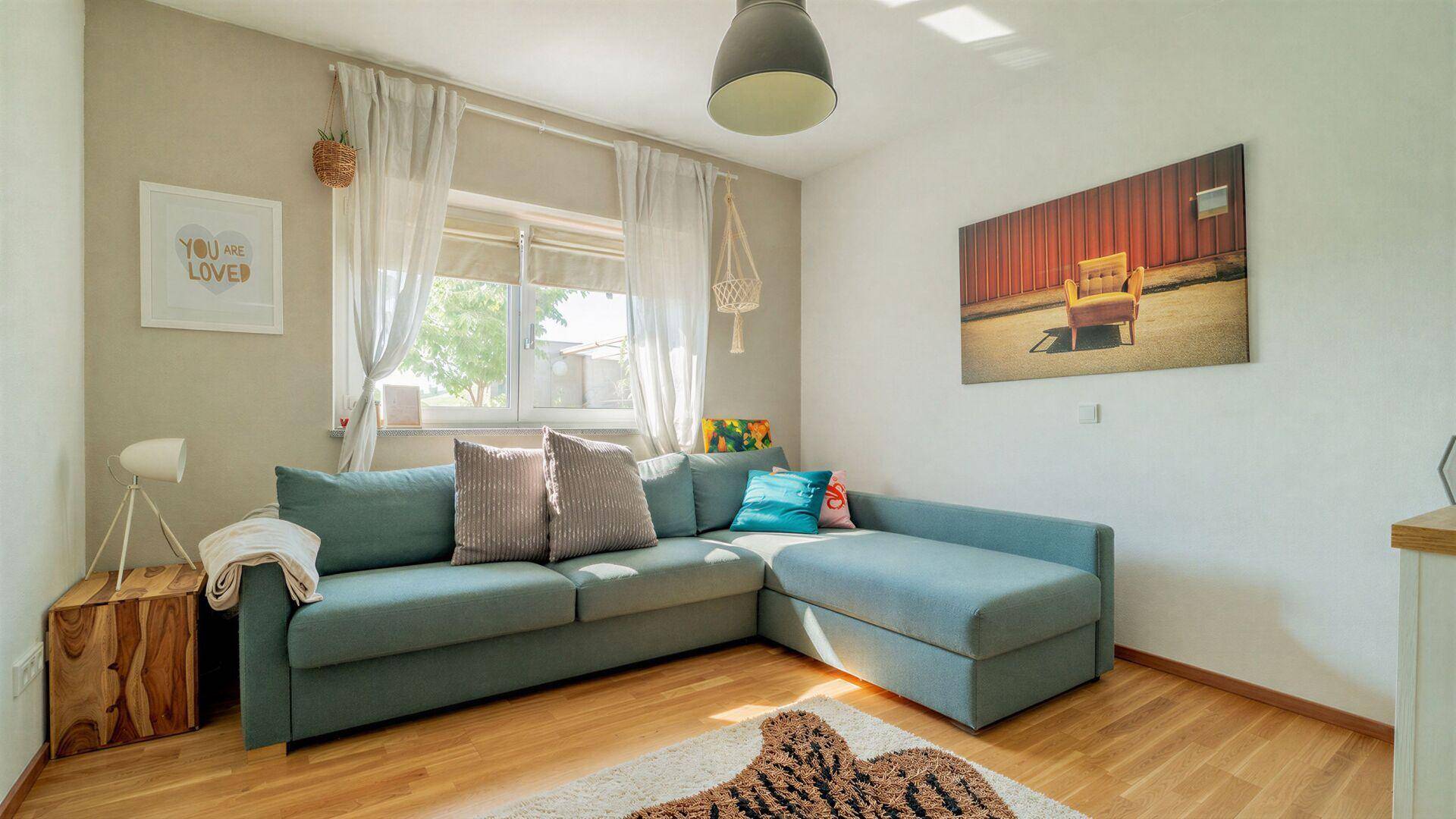 Gemütliches Schlafzimmer mit Holzboden, bequemer Couch und hellem Fenster, einladend gestaltet.