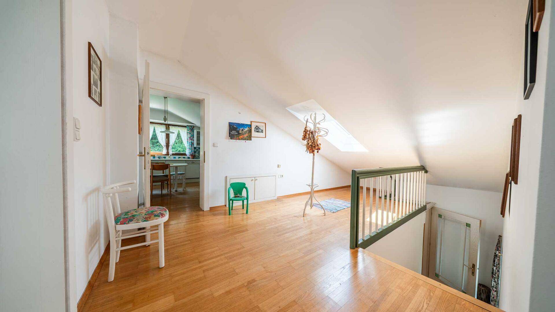 Heller Flur im Dachgeschoss mit Holzparkett und Dachfenster, führt zu weiteren Räumen.