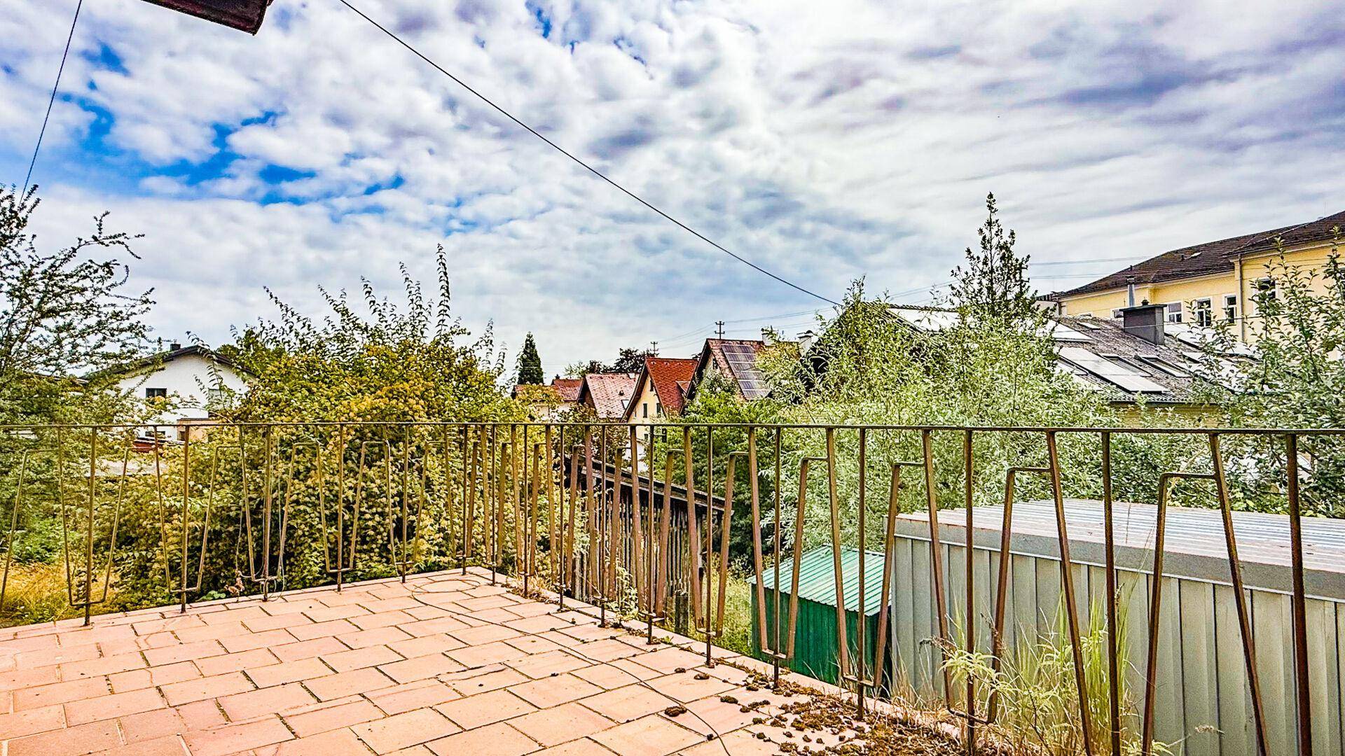 Kleiner Balkon mit Terrakottafliesen und Metallgeländer, bietet einen Blick ins Grüne.