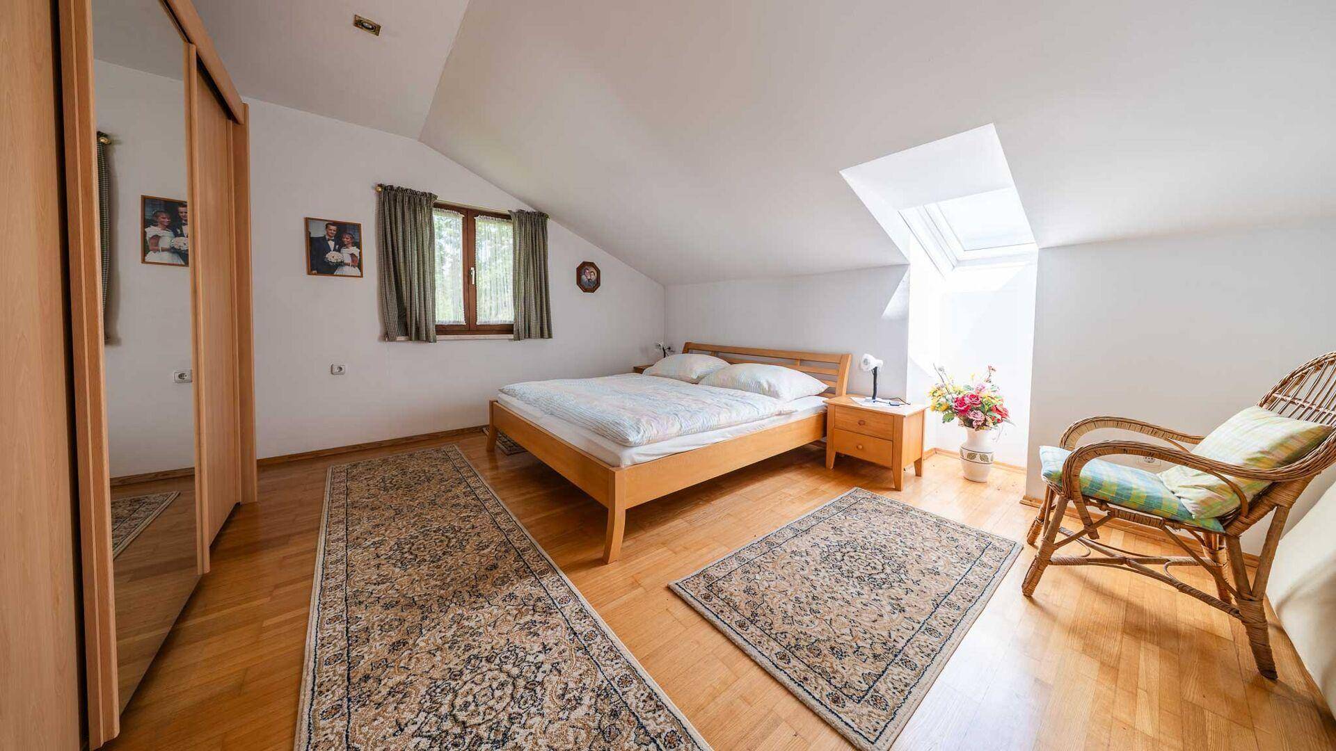 Helles Schlafzimmer im Dachgeschoss mit Holzparkett, Dachschräge und Dachfenster.