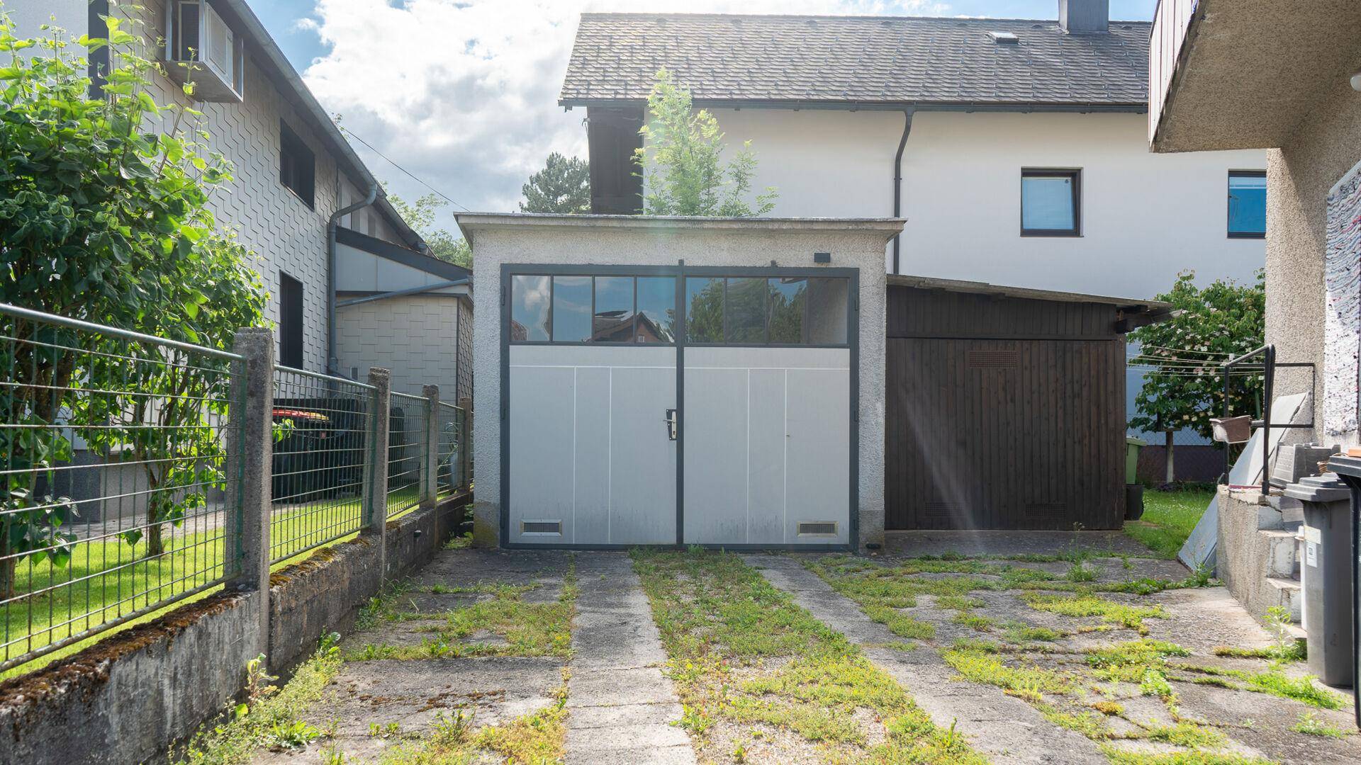 Freistehende Garage mit zwei Toren und einer Zufahrt aus Betonplatten.