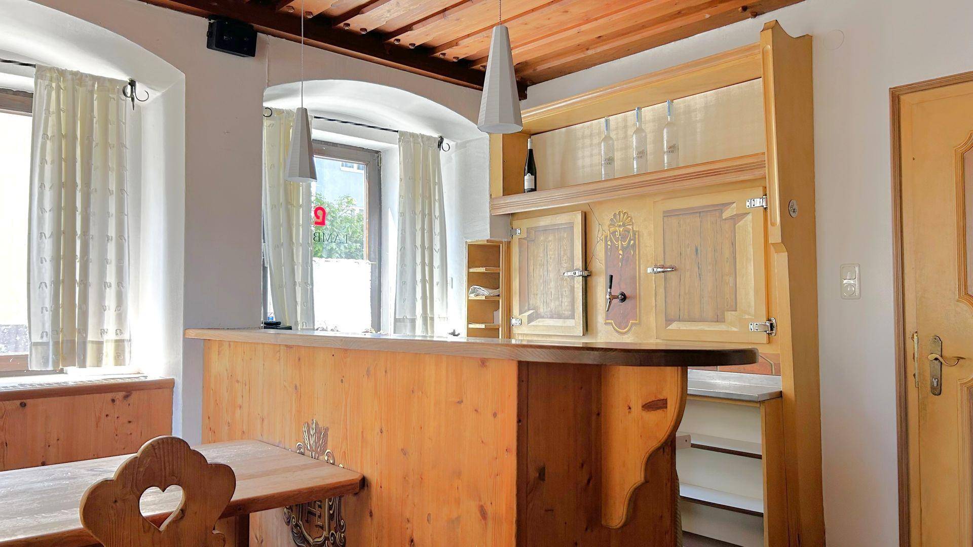 Gemütlicher Barbereich mit Holztheke, traditionellen Holzmöbeln und Fenstern mit Vorhängen.