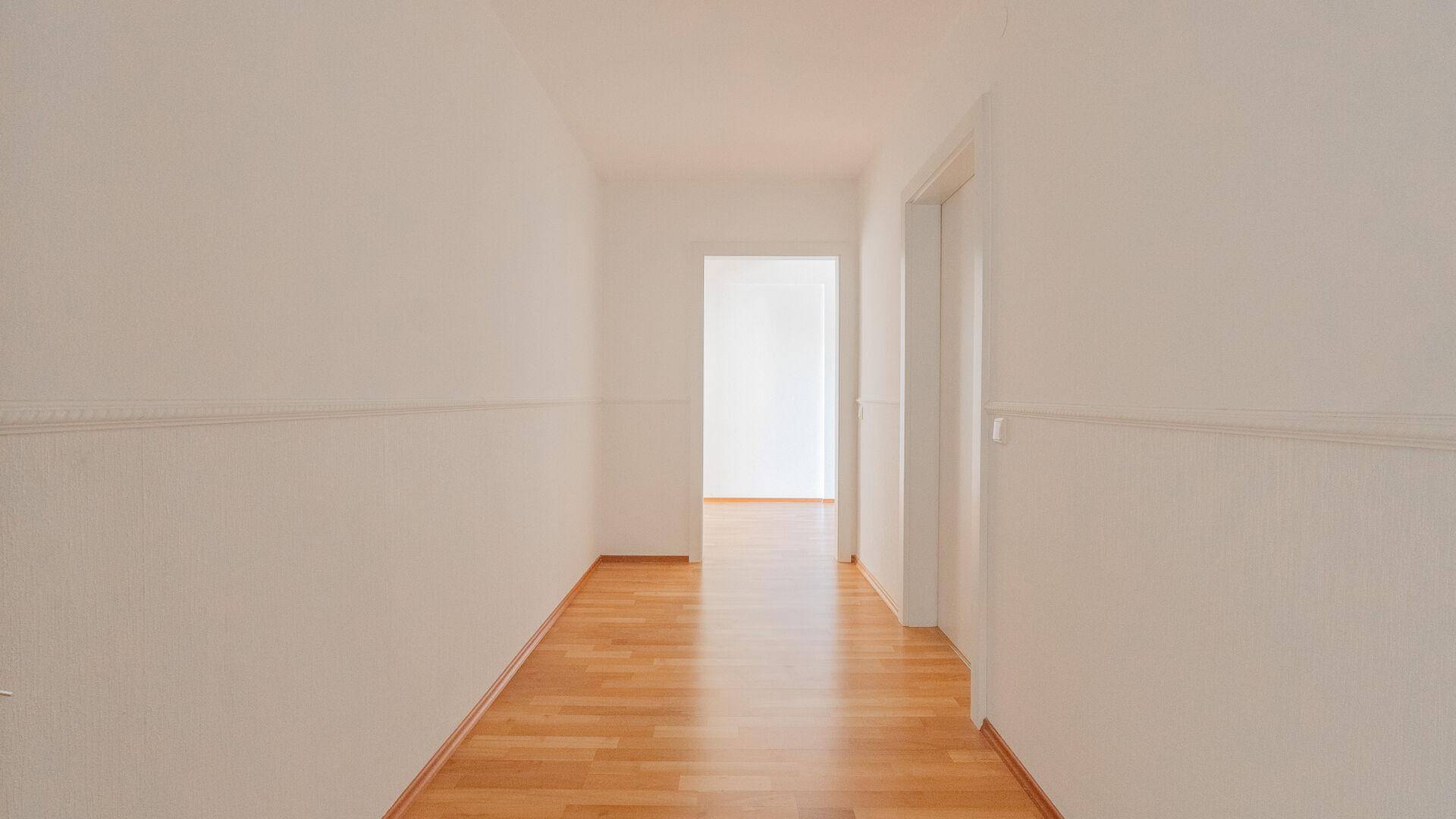 Heller Flur mit Holzparkettboden, der zu weiteren Räumen führt.