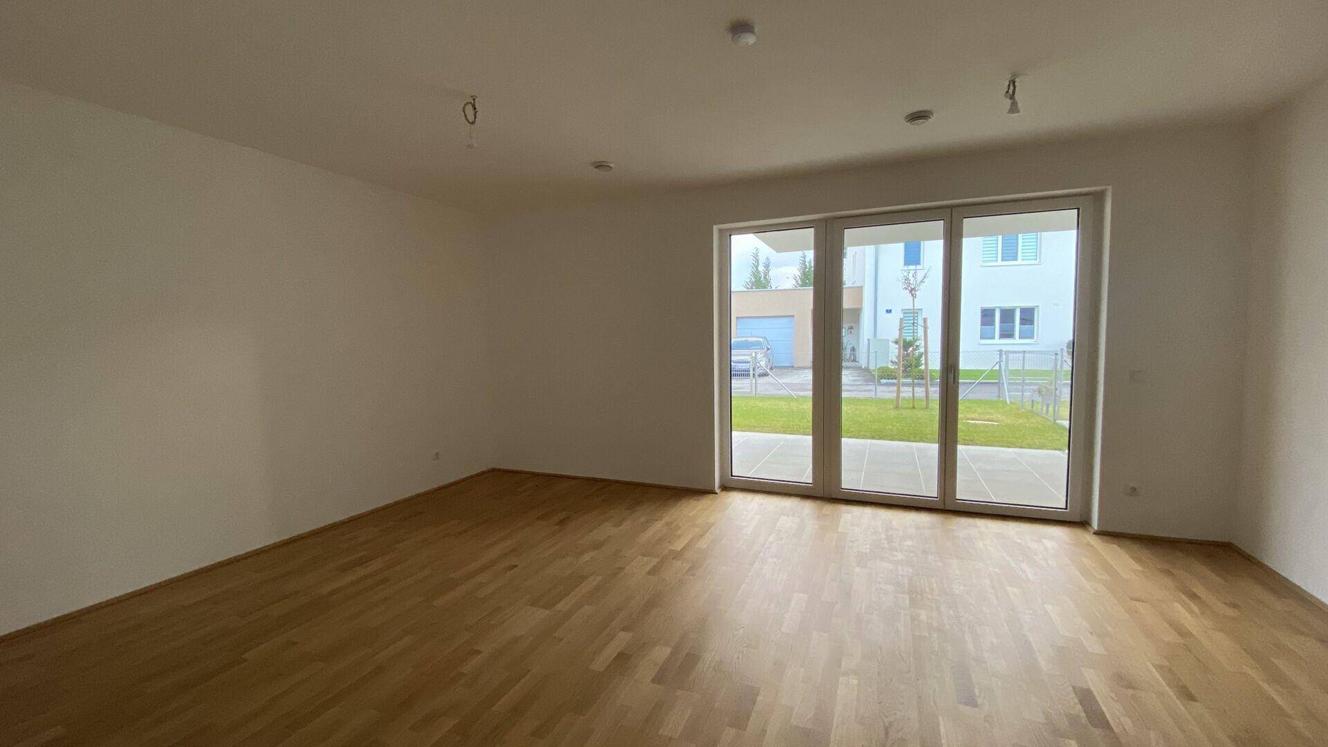 Heller Wohnbereich mit Parkettboden und großen Schiebetüren zum Garten.