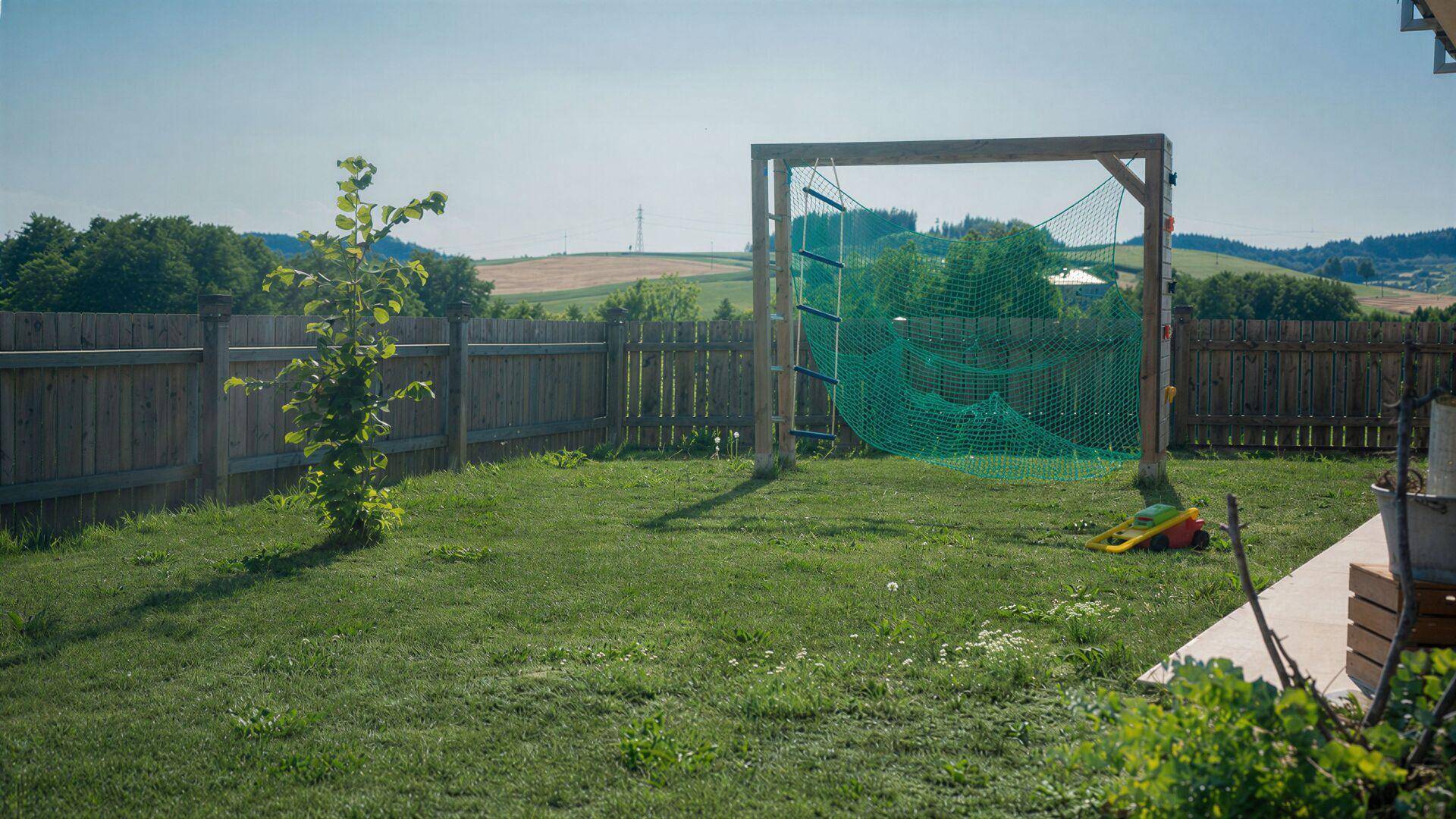 Grüner Gartenbereich mit Rasenfläche und einem Klettergerüst, ideal für Kinder zum Spielen.