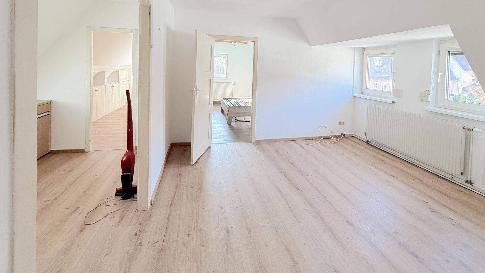 Heller Raum im Dachgeschoss mit Laminatboden und Zugang zu weiteren Zimmern.