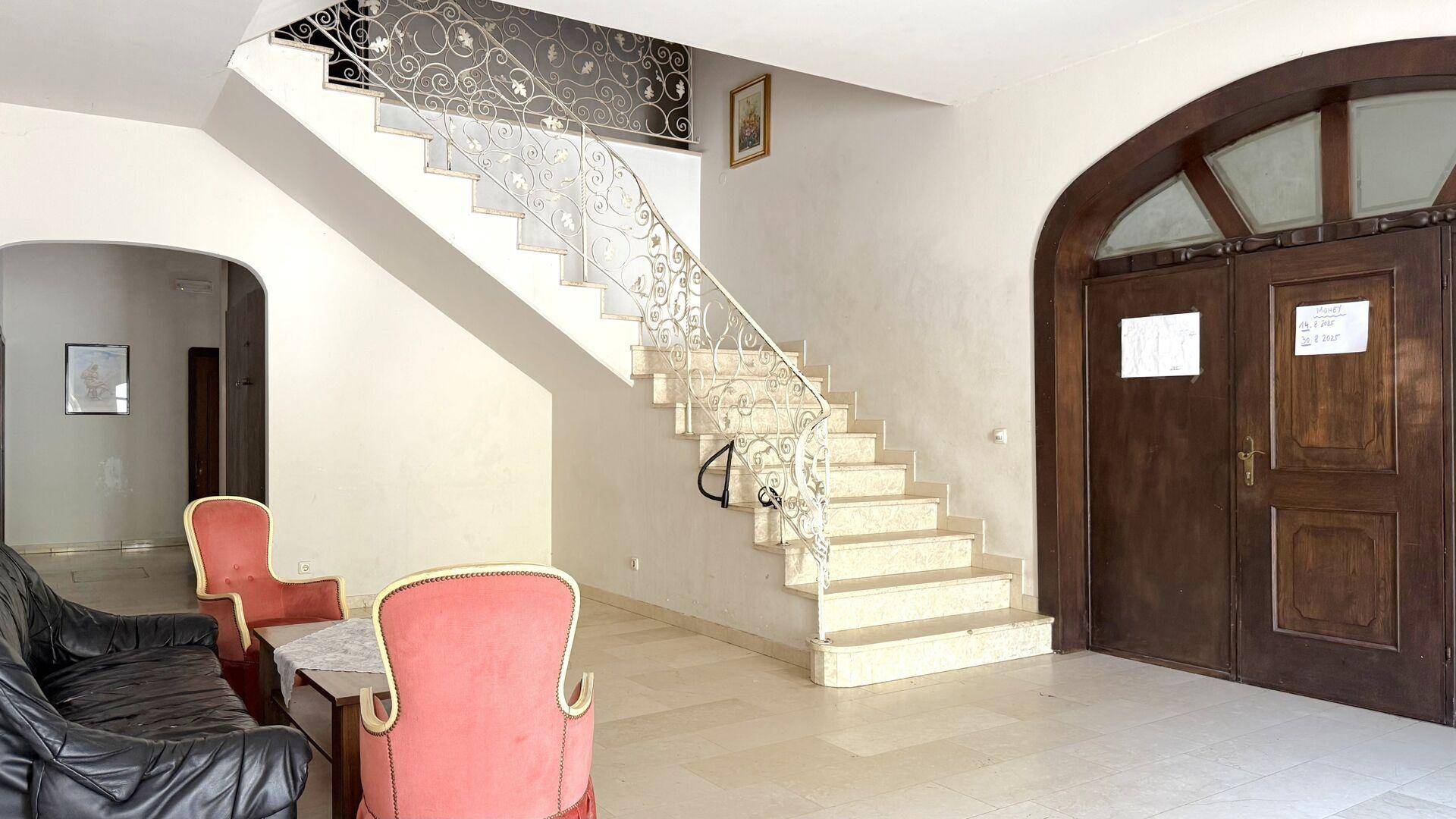 Geräumige Eingangshalle mit Marmorboden, eleganter Treppe und schmiedeeisernem Geländer.