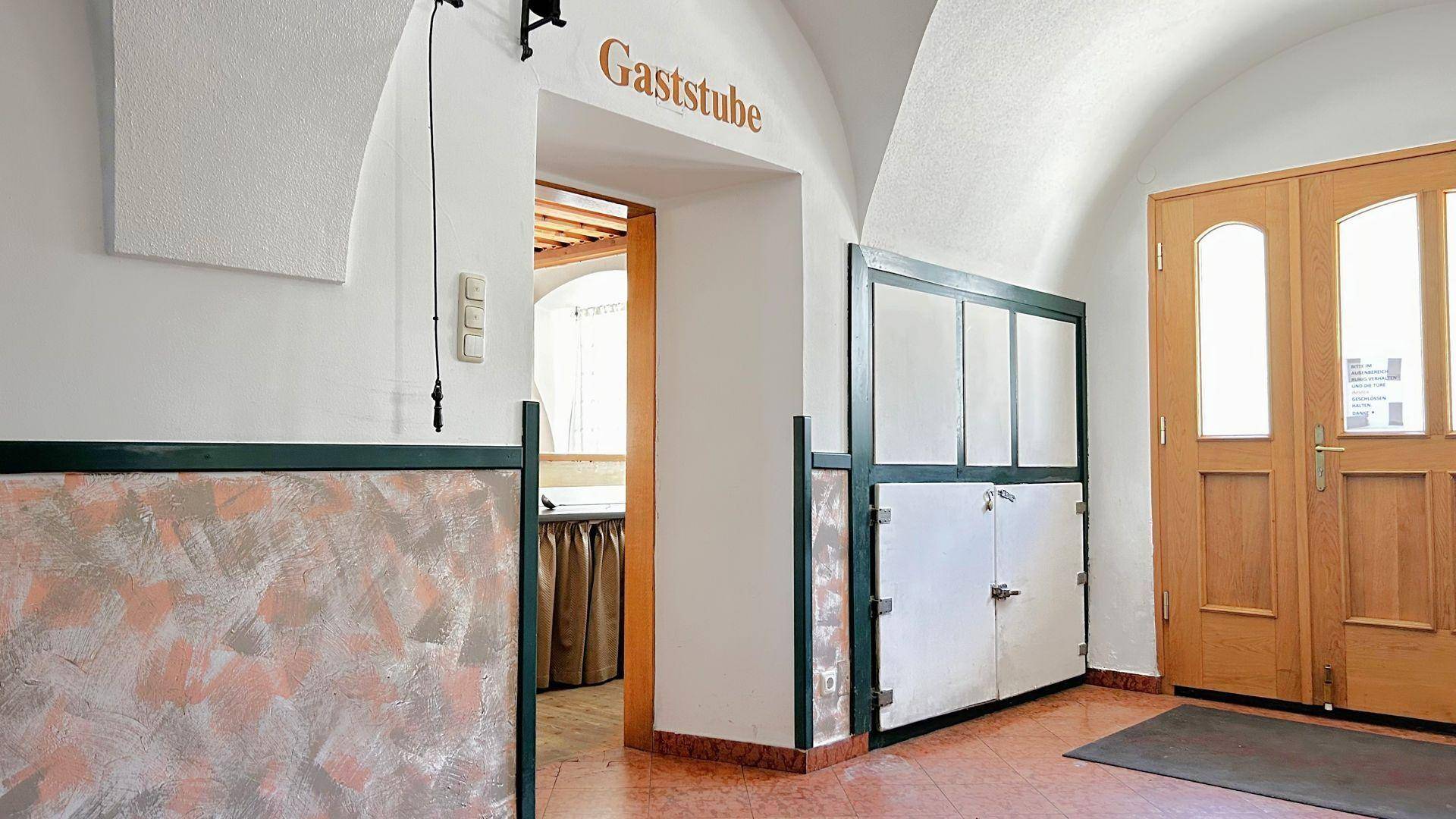 Eingangsbereich mit gewölbter Decke, Terrakotta-Boden und Zugang zur Gaststube.