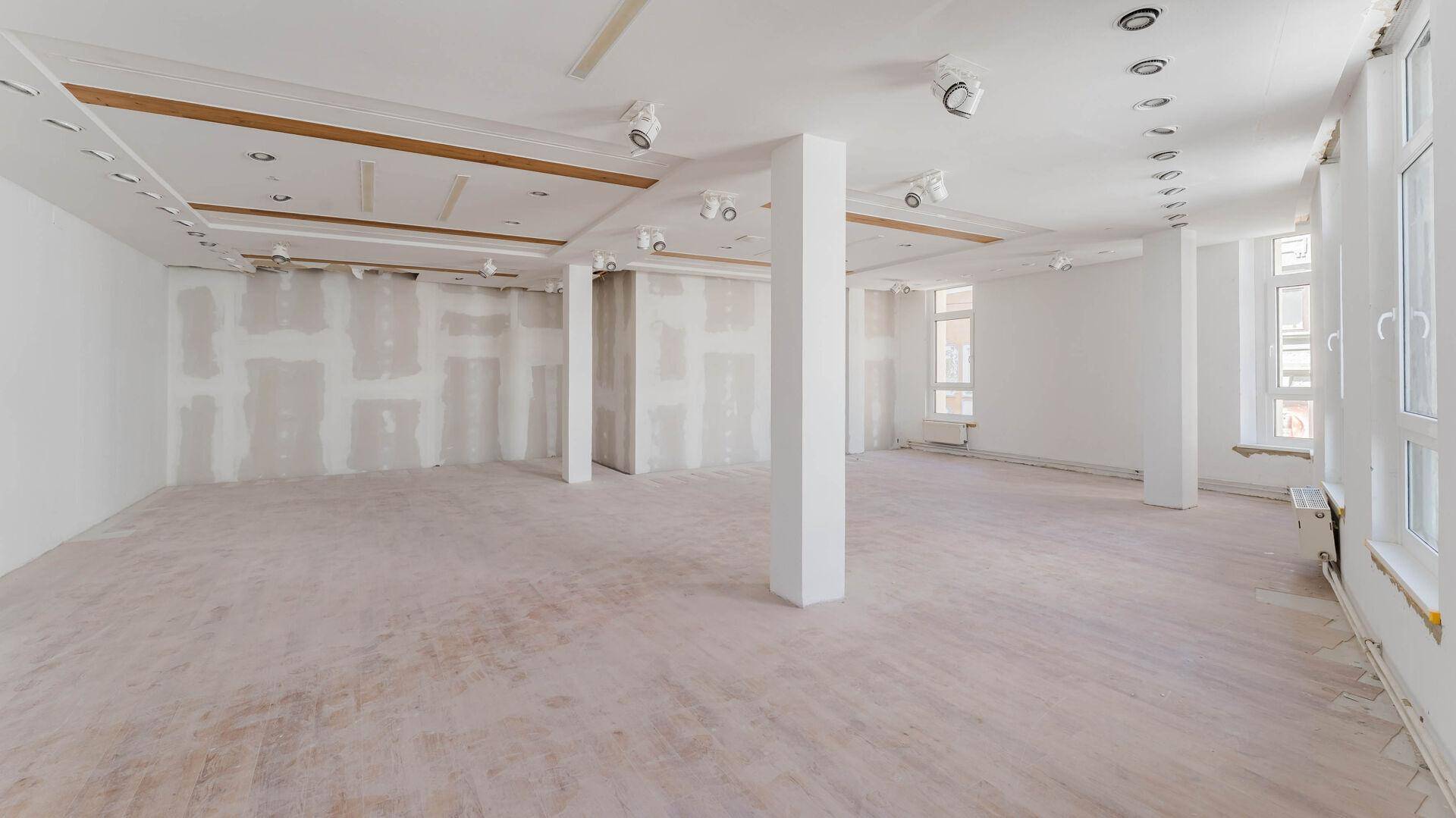 Großer, leerer Raum mit hohen Decken und vielen Fenstern, bereit für den Ausbau.
