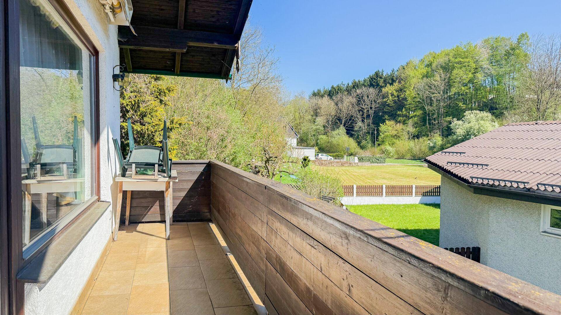 Sonniger Balkon mit Holzboden und Blick ins Grüne, ideal zum Entspannen im Freien.