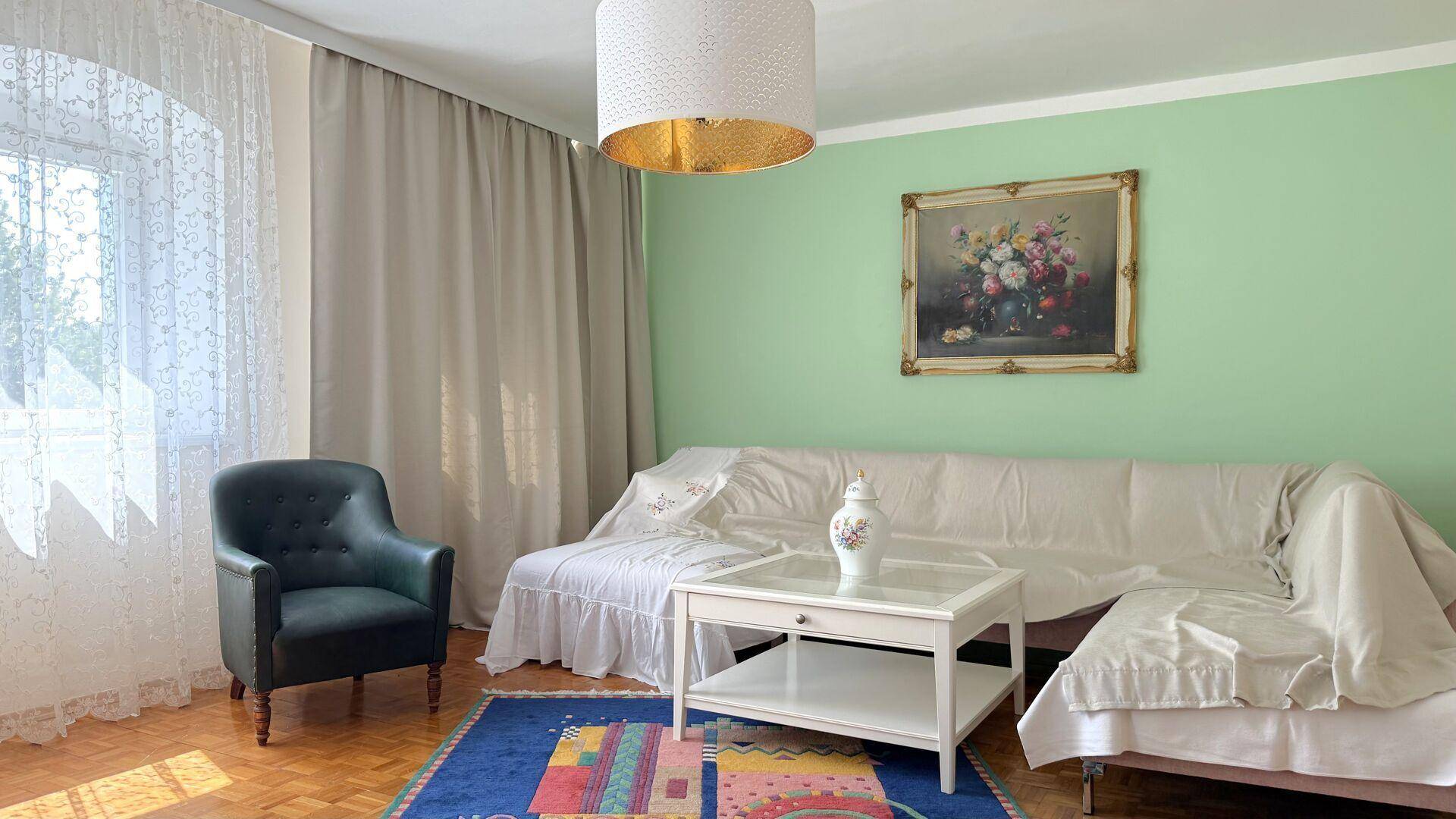 Helles Wohnzimmer mit grünen Wänden, Parkettboden und einem bequemen Sofa.