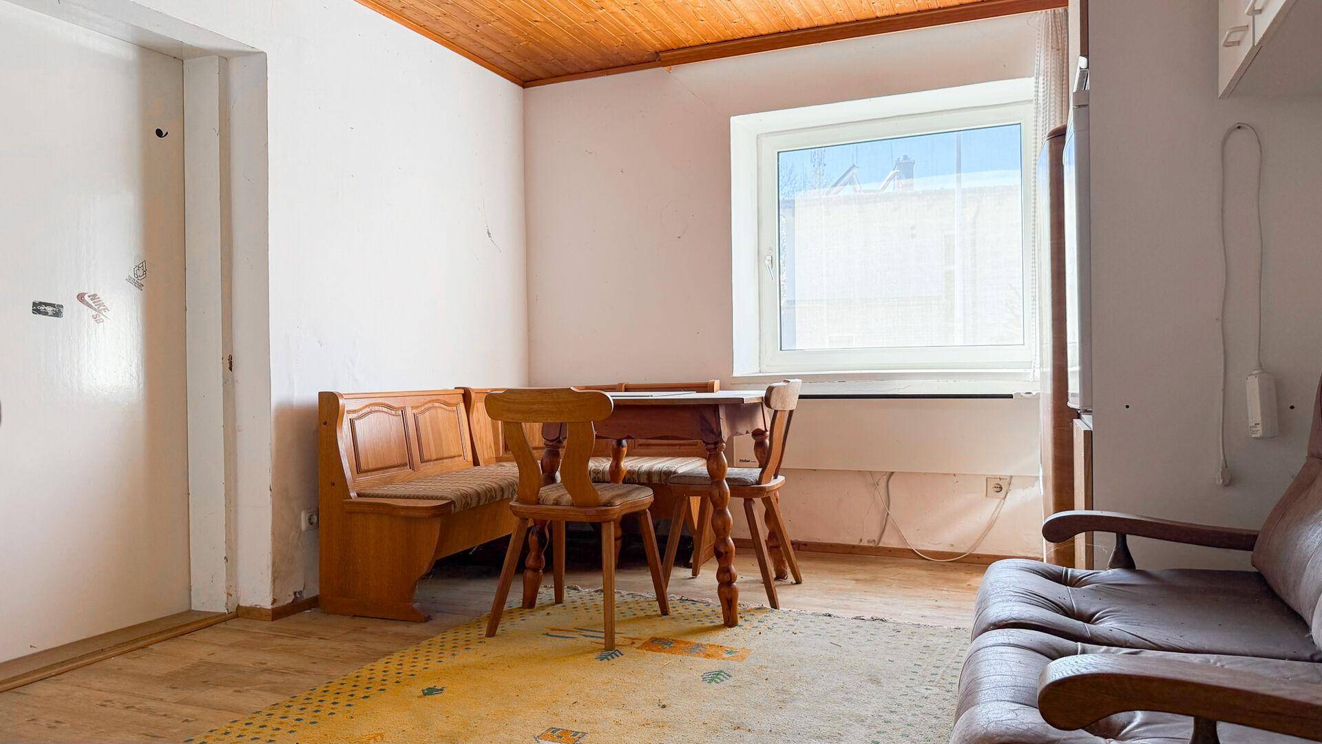 Gemütlicher Wohnbereich mit Holztisch, Eckbank und Sofa, unter einer Holzdecke.