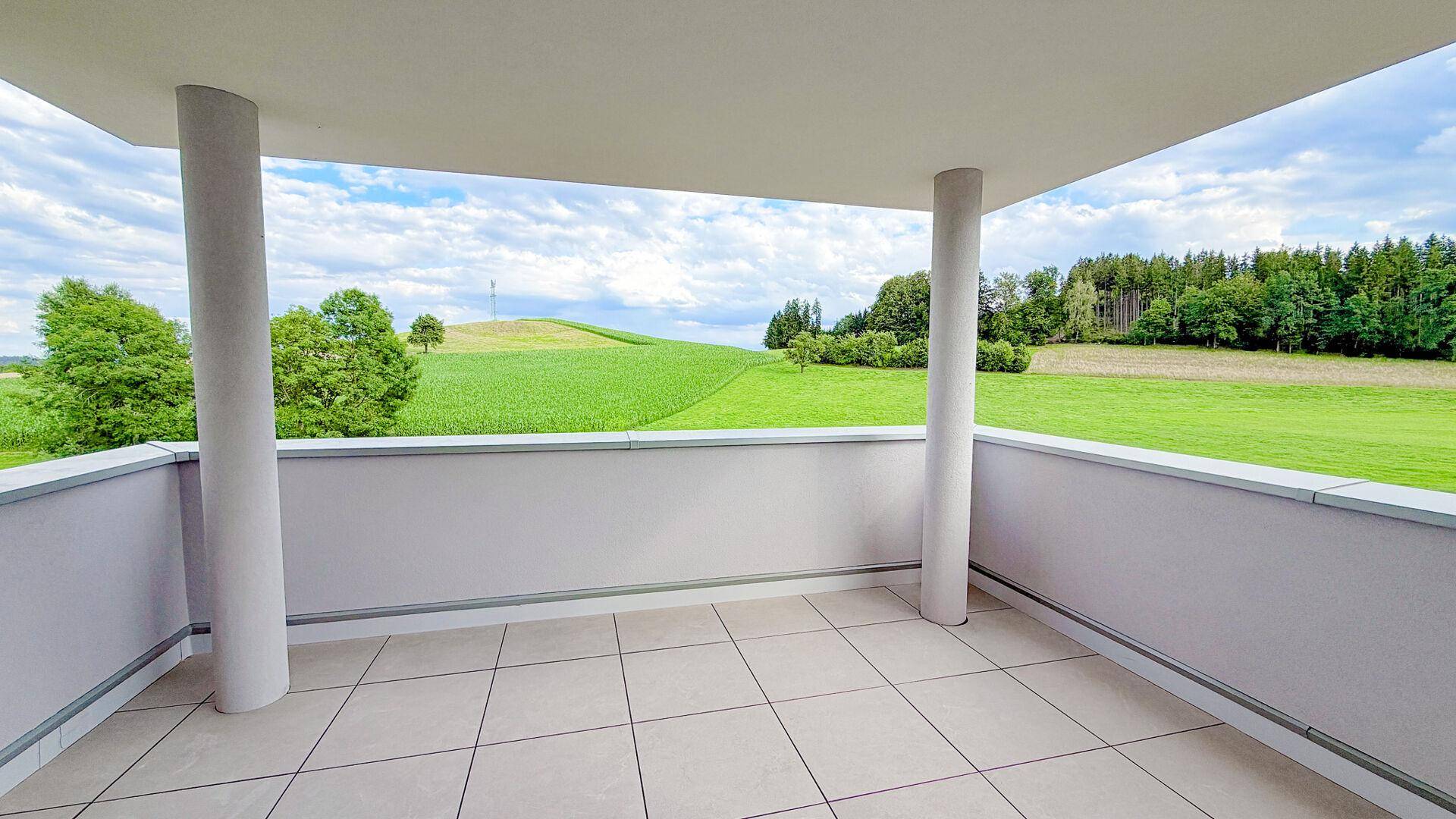 Geräumiger, überdachter Balkon mit Fliesen und Panoramablick auf die idyllische Natur.