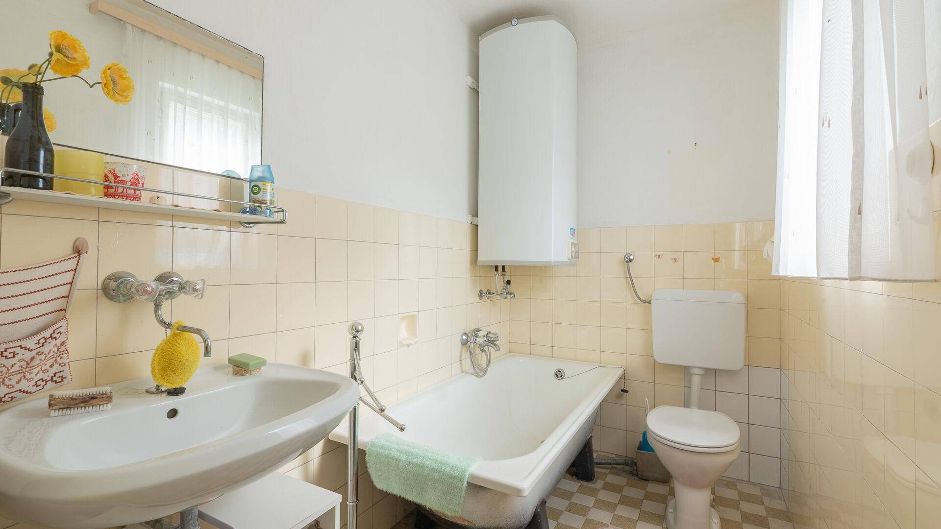 Badezimmer mit Badewanne, Waschbecken und WC, in hellen Fliesen gehalten.