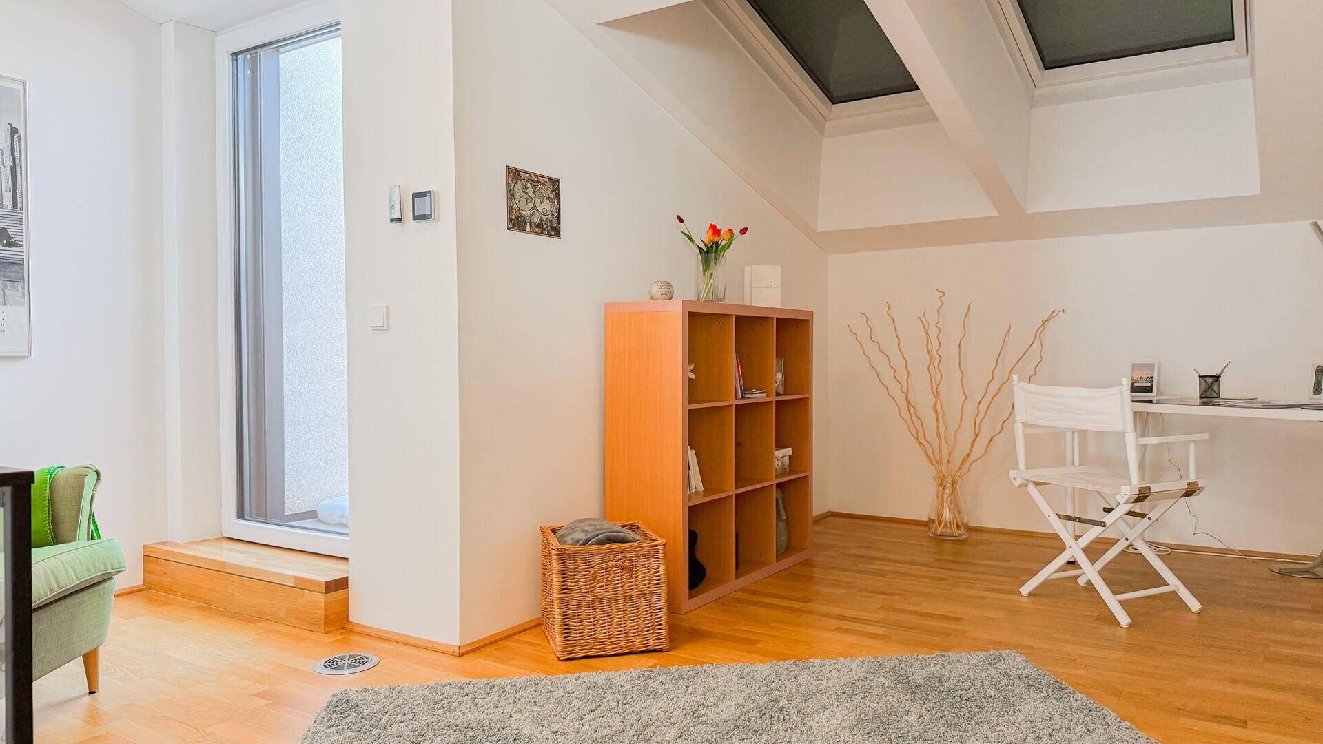 Helles Zimmer mit Dachschrägen, Dachfenstern und einem Arbeitsbereich, ideal für kreatives Arbeiten.