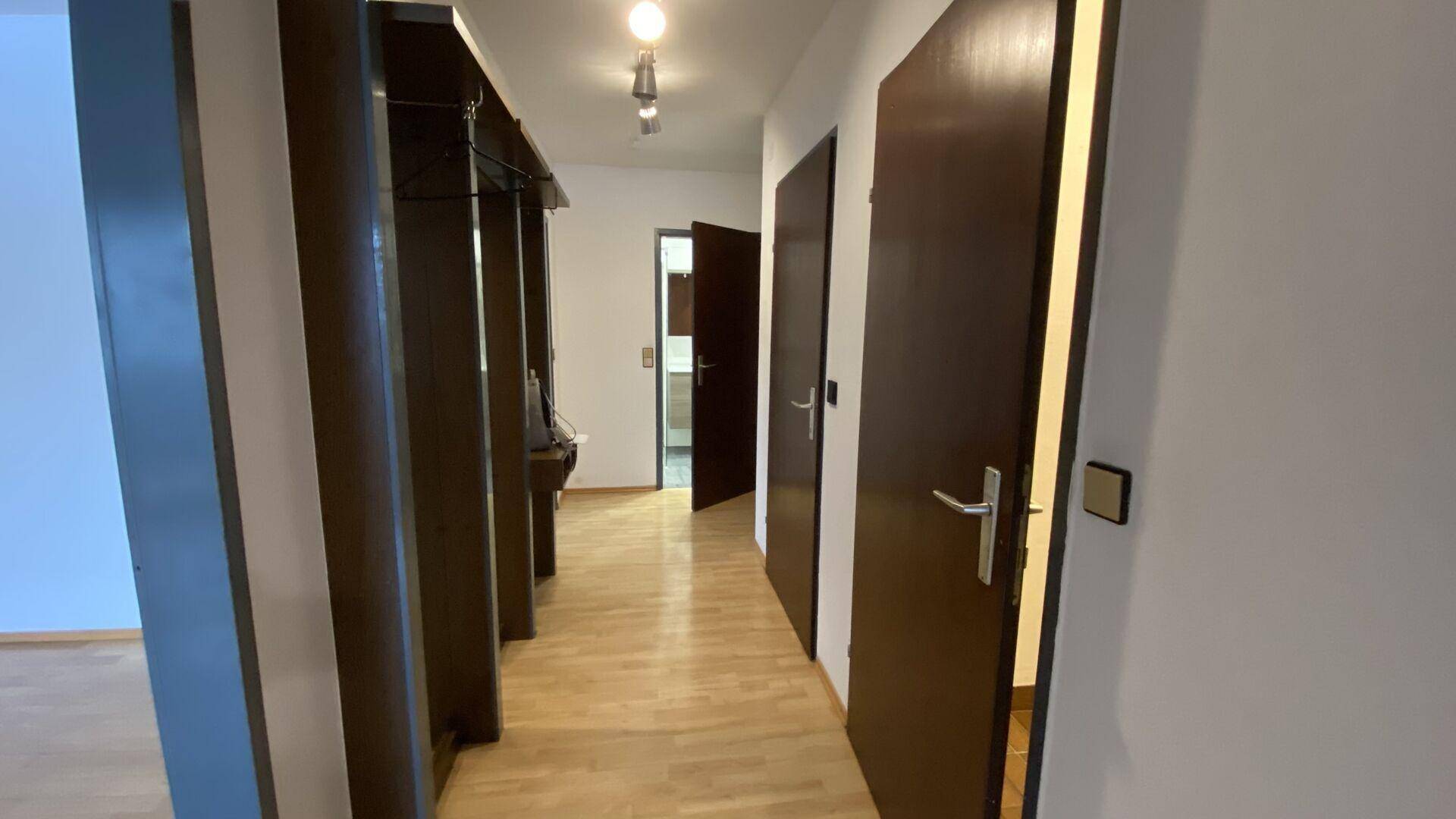 Langer Flur mit Holzboden und mehreren Türen, der zu verschiedenen Räumen führt.