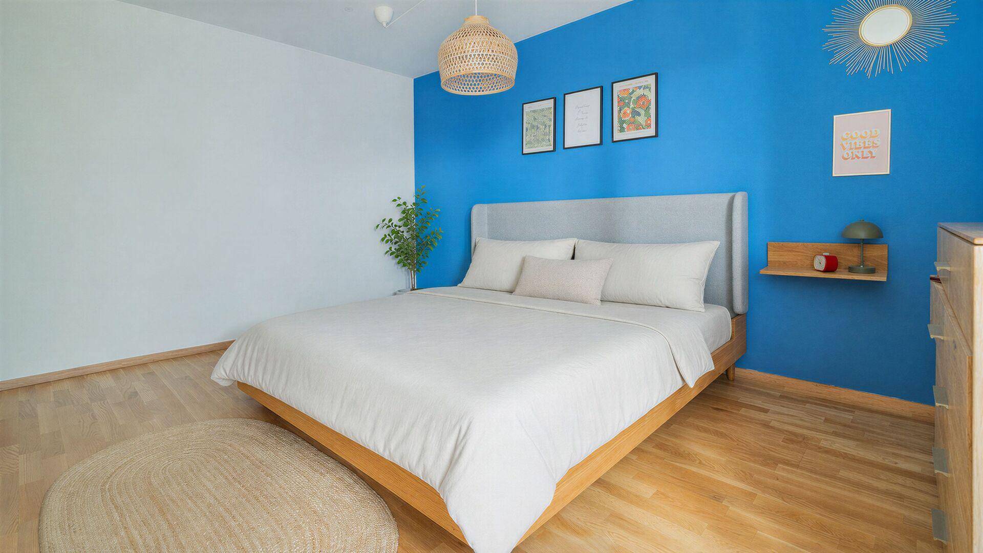 Modernes Schlafzimmer mit Holzboden, blauer Akzentwand und minimalistischer Einrichtung, sehr hell.