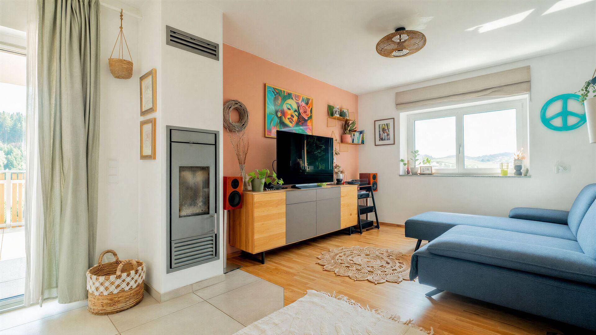 Gemütliches Wohnzimmer mit Holzboden, Kaminofen und farbenfroher Dekoration, hell und einladend.