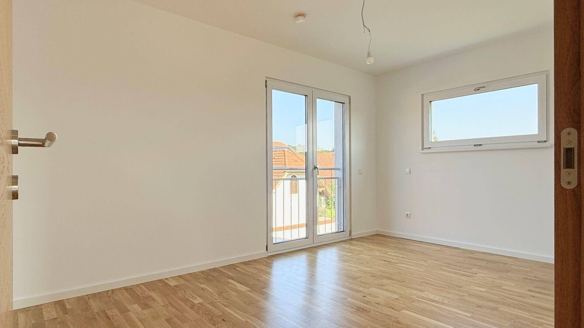 Helles Zimmer mit Parkettboden und einem französischen Balkon, der viel Licht spendet.