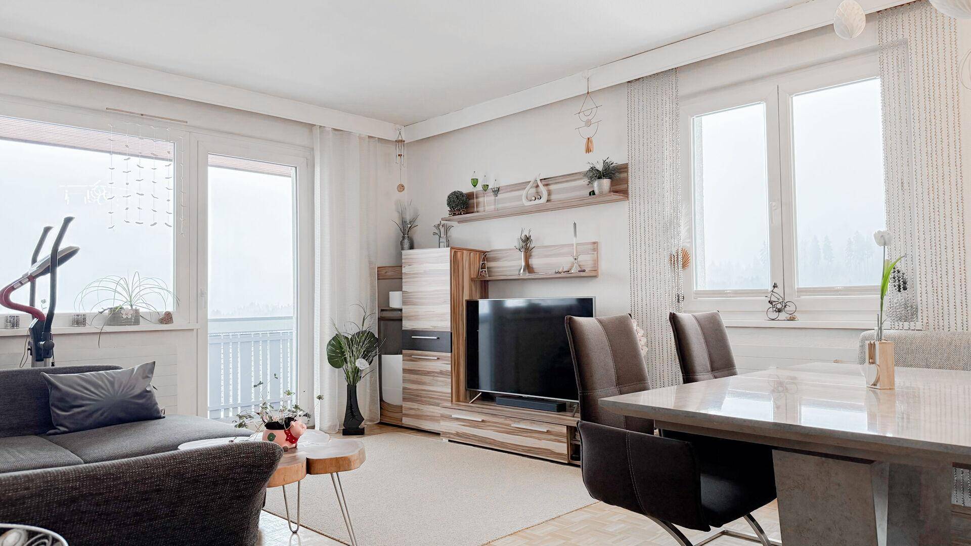 Heller Wohn-Essbereich mit modernem Mobiliar, Parkettboden und Zugang zum Balkon.
