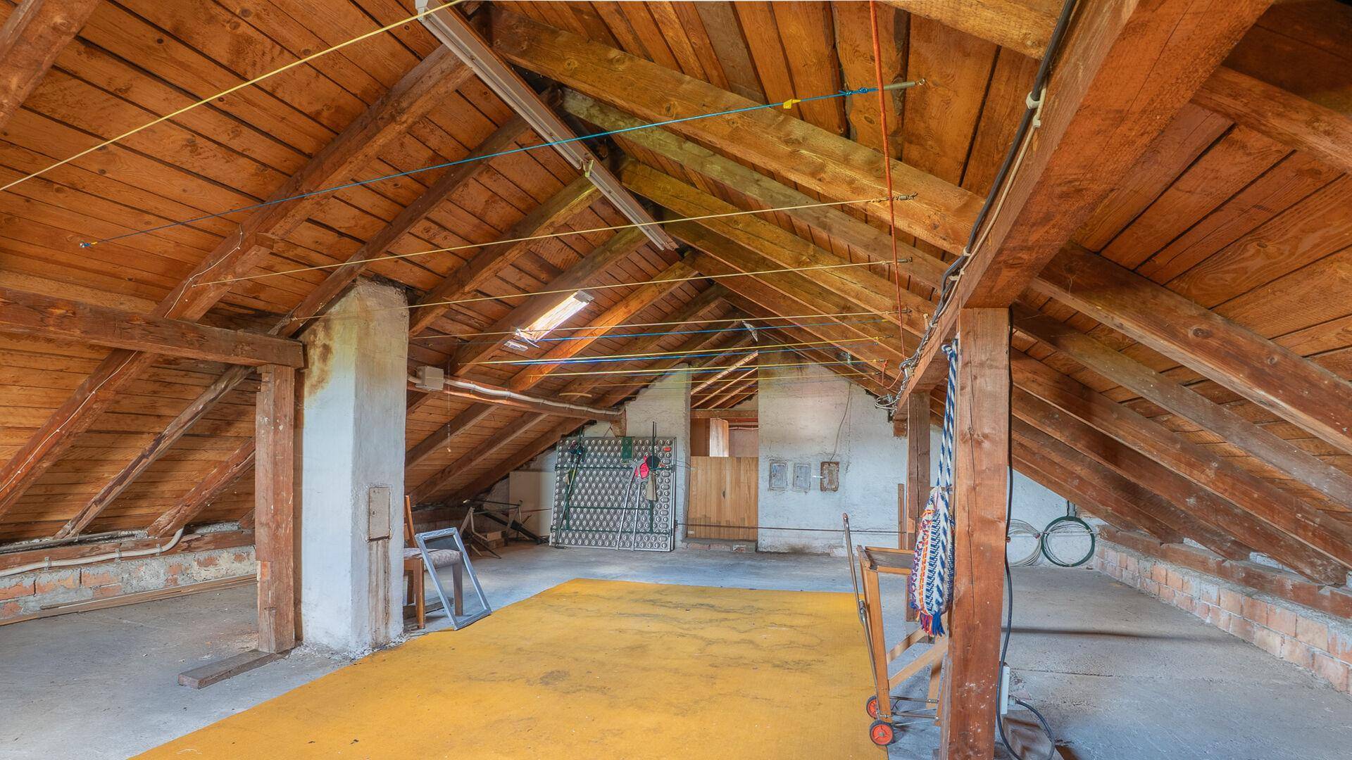 Geräumiger Dachboden mit sichtbaren Holzbalken und Dachfenster, viel Stauraum.