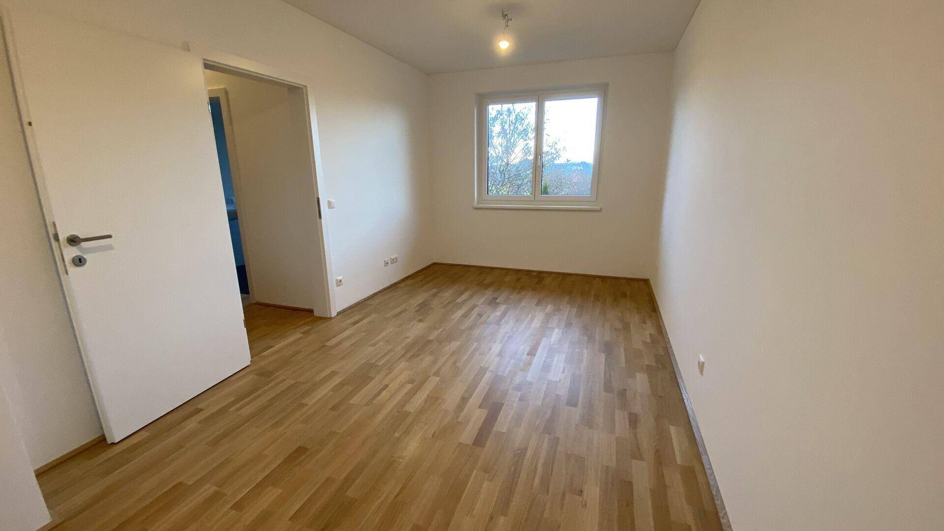 Geräumiges Schlafzimmer mit Parkettboden und Fenster, bereit zur individuellen Gestaltung.