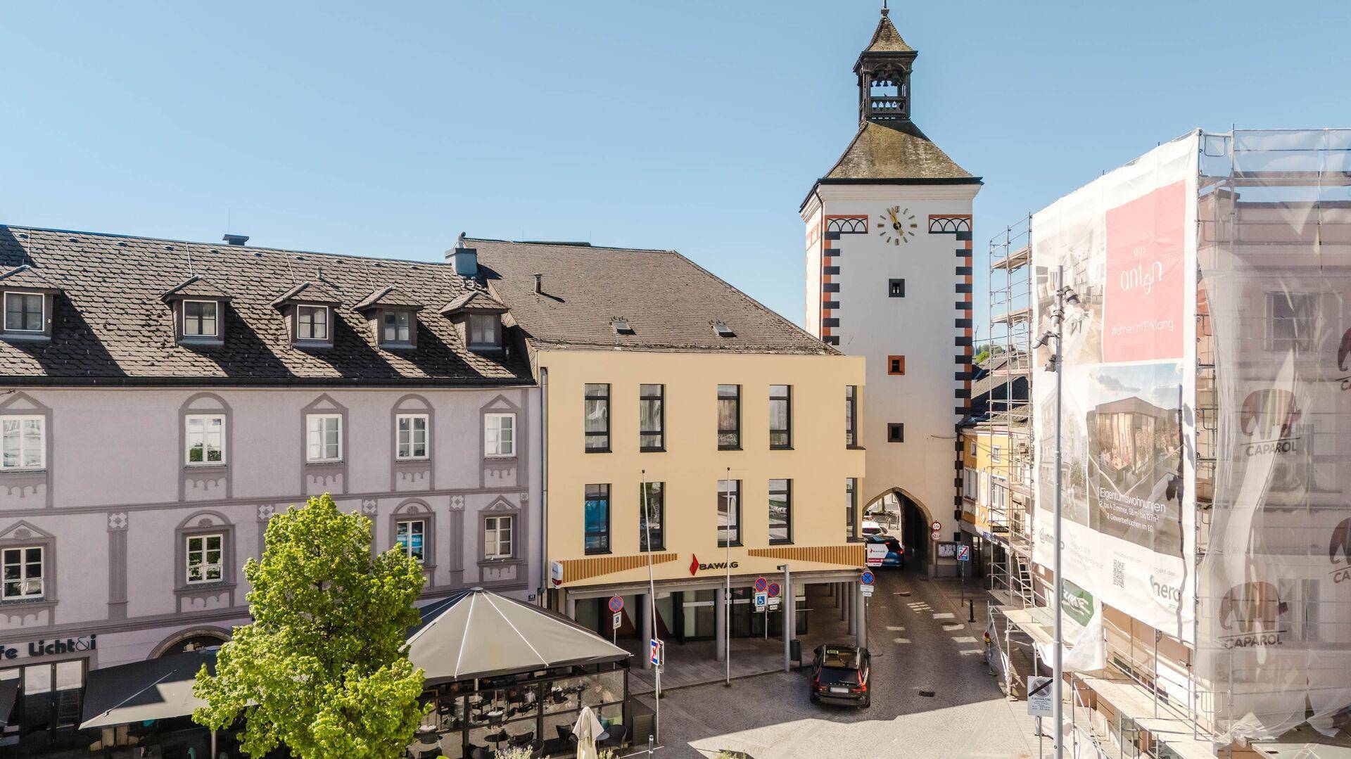 Stadtansicht mit historischen und modernen Gebäuden, einem Uhrturm und einer Baustelle.