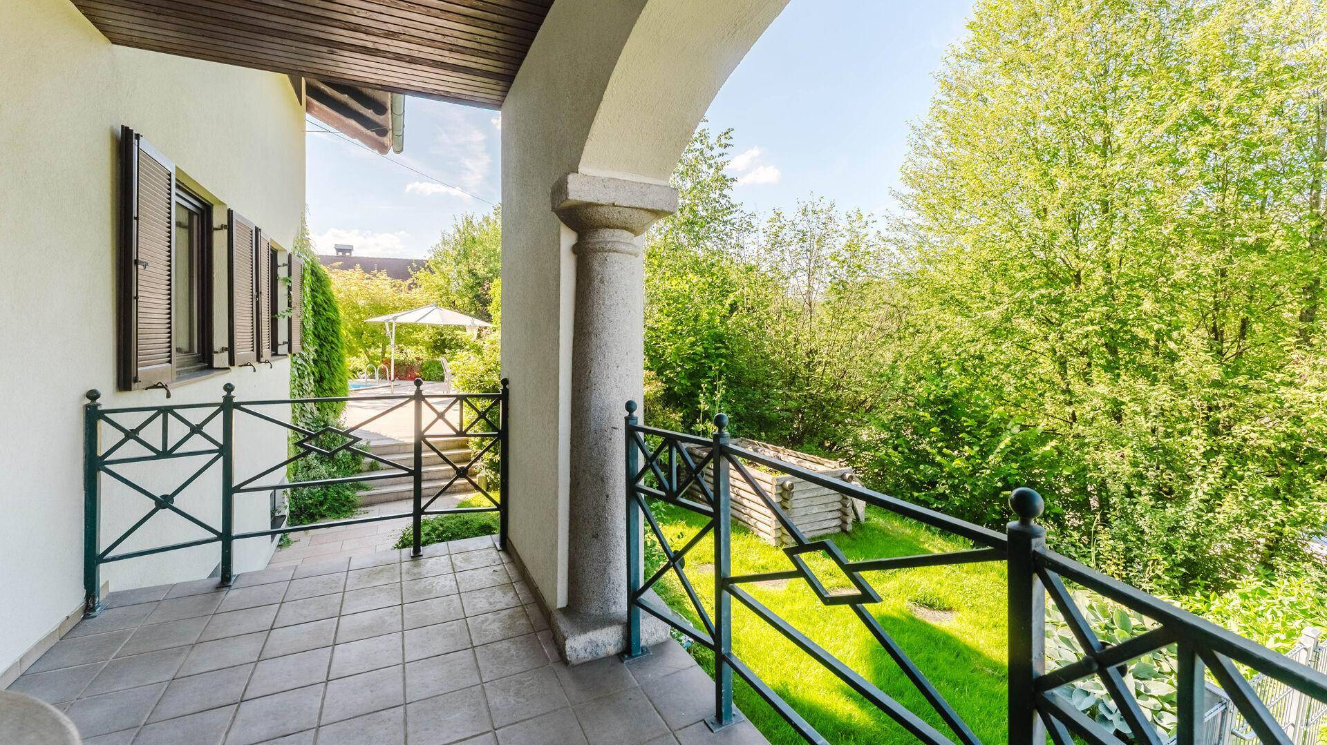 Balkon mit schmiedeeisernem Geländer und weitem Blick in den Garten.