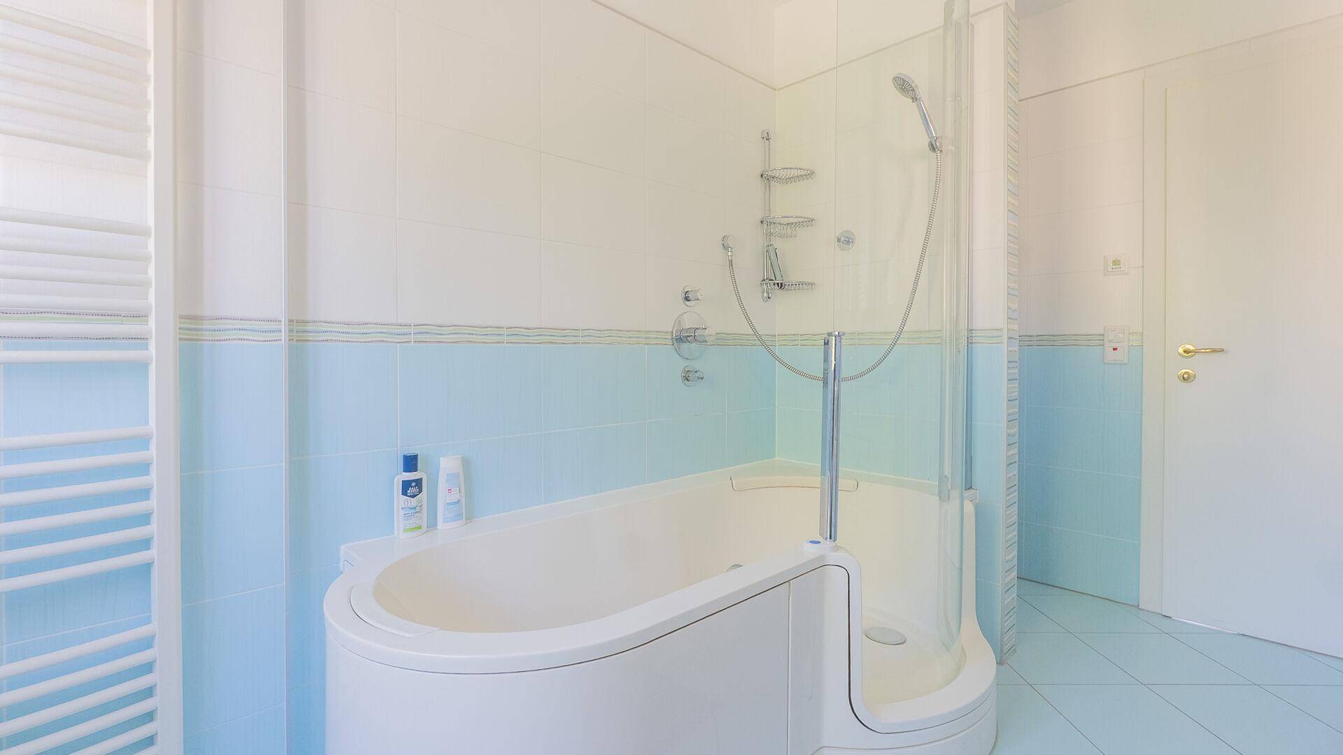 Modernes Badezimmer mit Badewanne, integrierter Dusche und beheiztem Handtuchhalter.